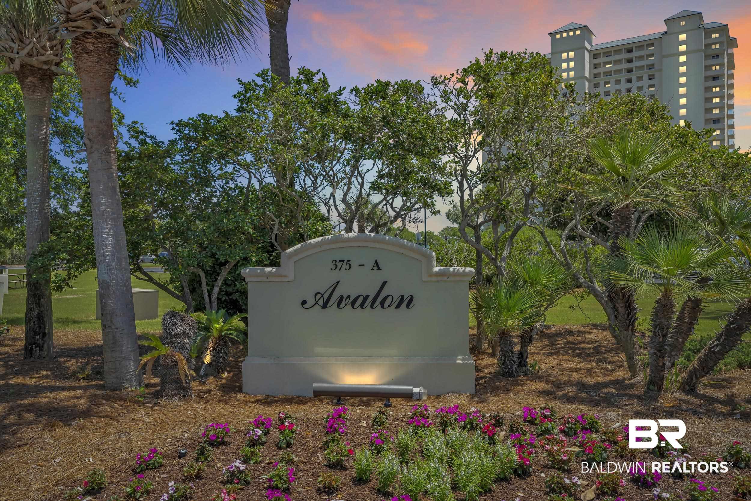 Image 2: Monument sign with architectural molding, featuring up-lighting, a landscaped flower bed, mature palm trees, and established foliage