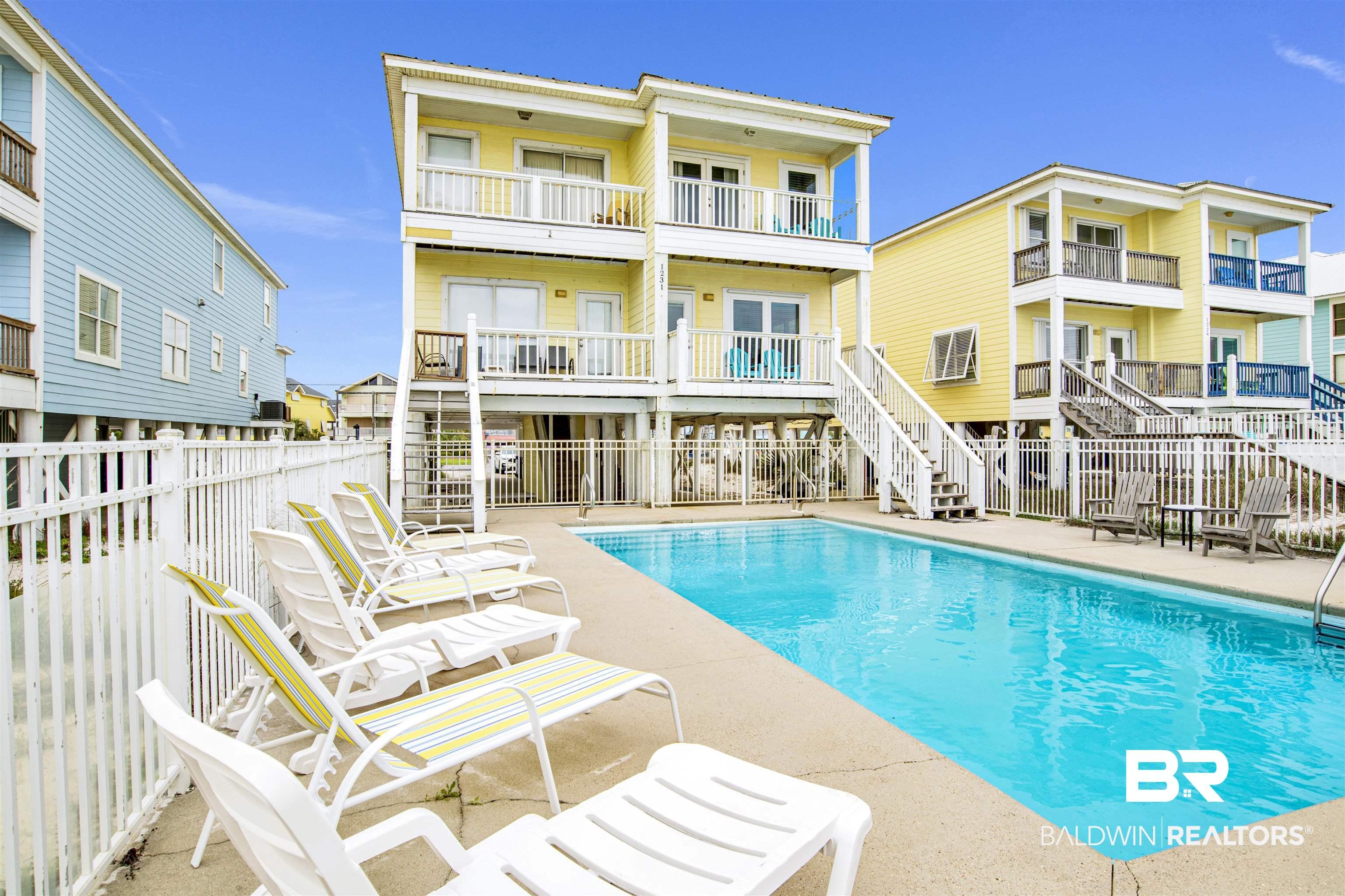 Image 1: Back of property with stairs, a community pool, and a patio