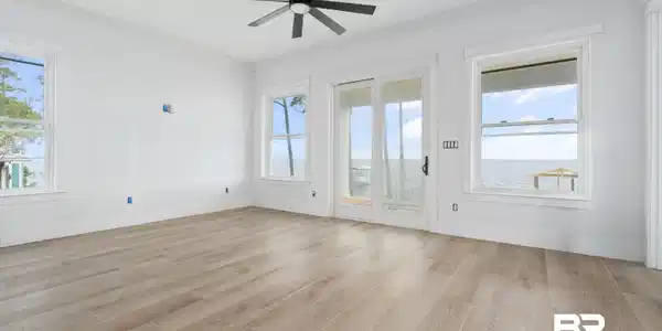 Image 2: Expansive room featuring light wood-finish flooring and a contemporary black ceiling fan