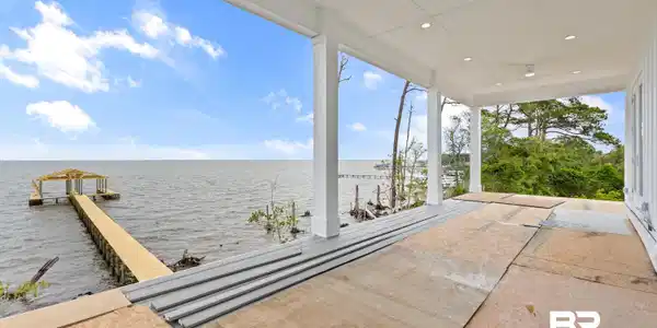 Image 3: Expansive covered porch featuring a waterside setting, a private pier with a covered boat dock, and surrounding mature trees