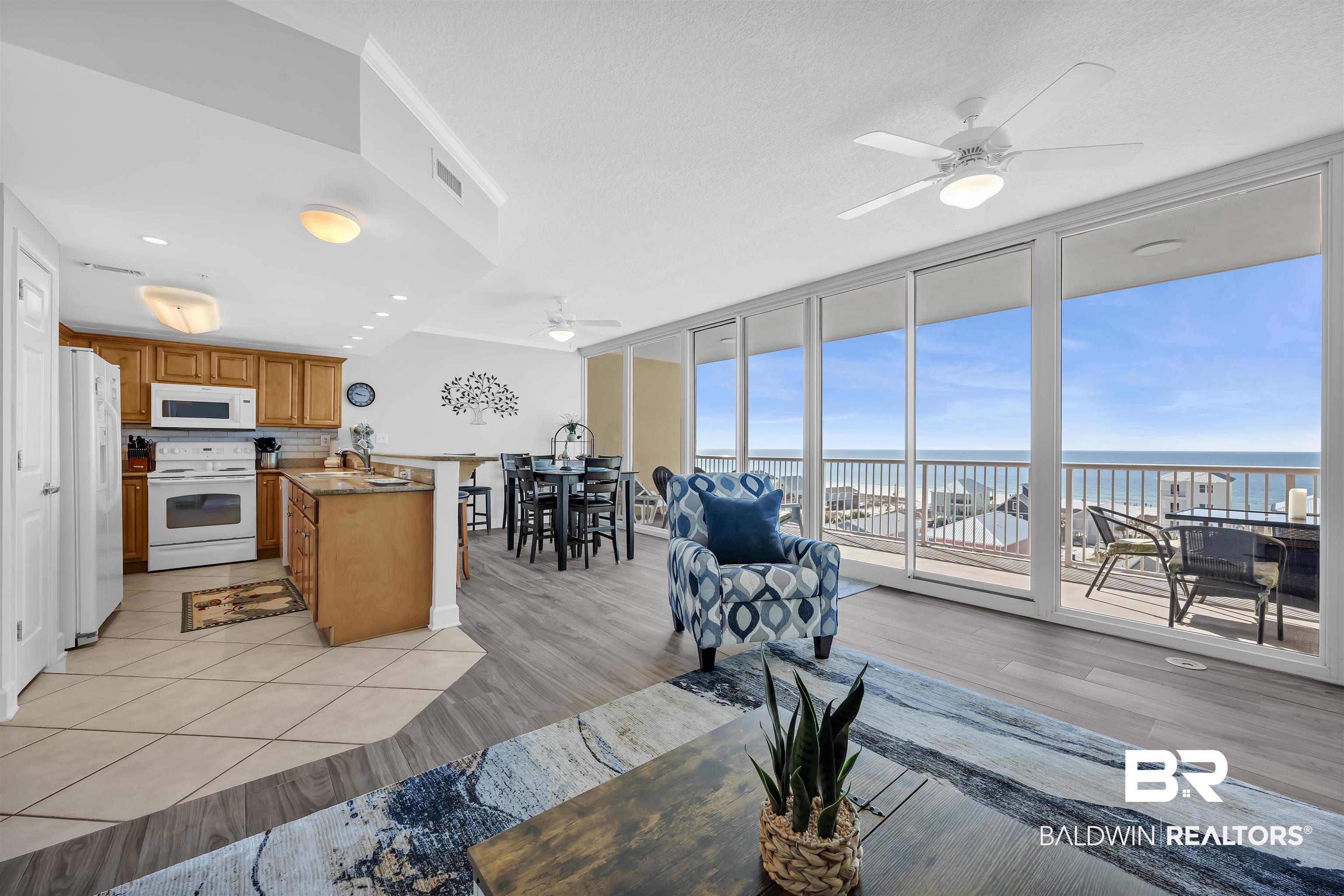 Image 3: Living area featuring expansive windows, ceiling fan, light wood-style flooring, a water view, and ornamental molding