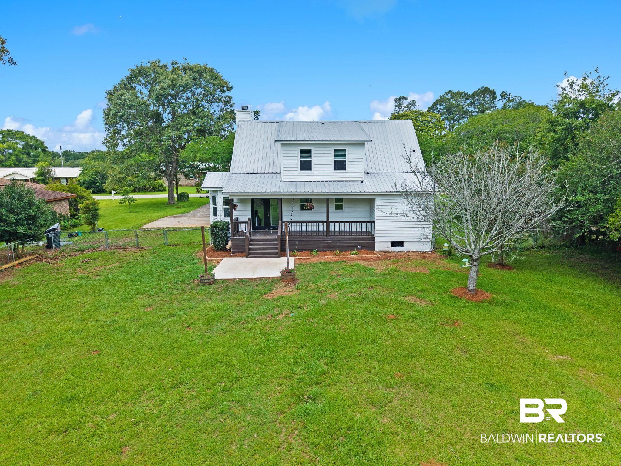 Image 2: White two-story home featuring a metal roof and a covered front porch with dark railings