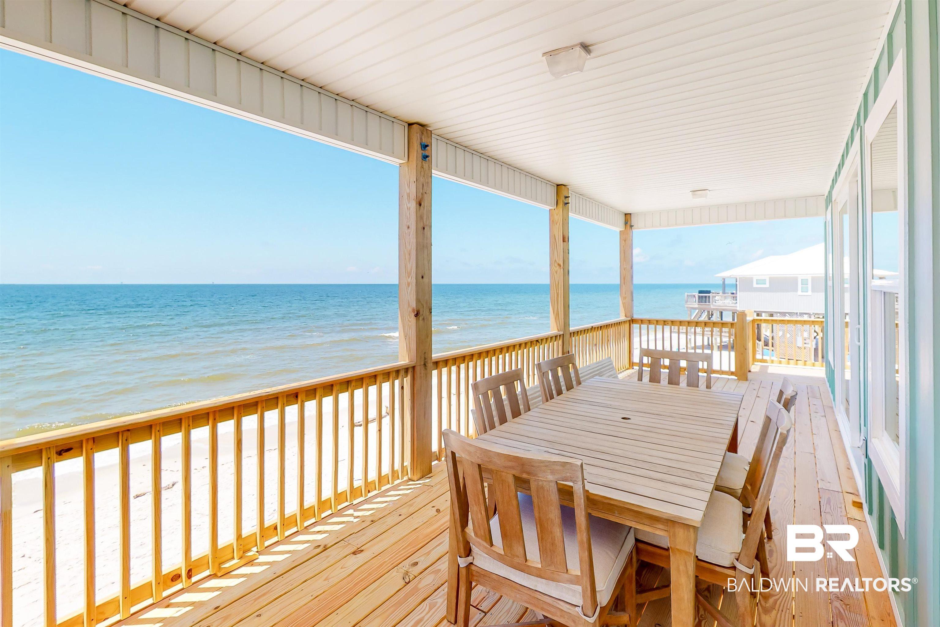Image 4: Wooden terrace featuring view of water and beach and outdoor dining space