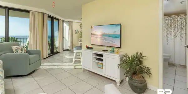 Image 4: Living area with light tile patterned floors, floor to ceiling windows, ceiling fan, and a water view