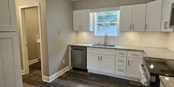 Image 2: Kitchen featuring white cabinetry, stone-finish countertops, subway tile backsplash, stainless steel appliances, and wood-finish flooring