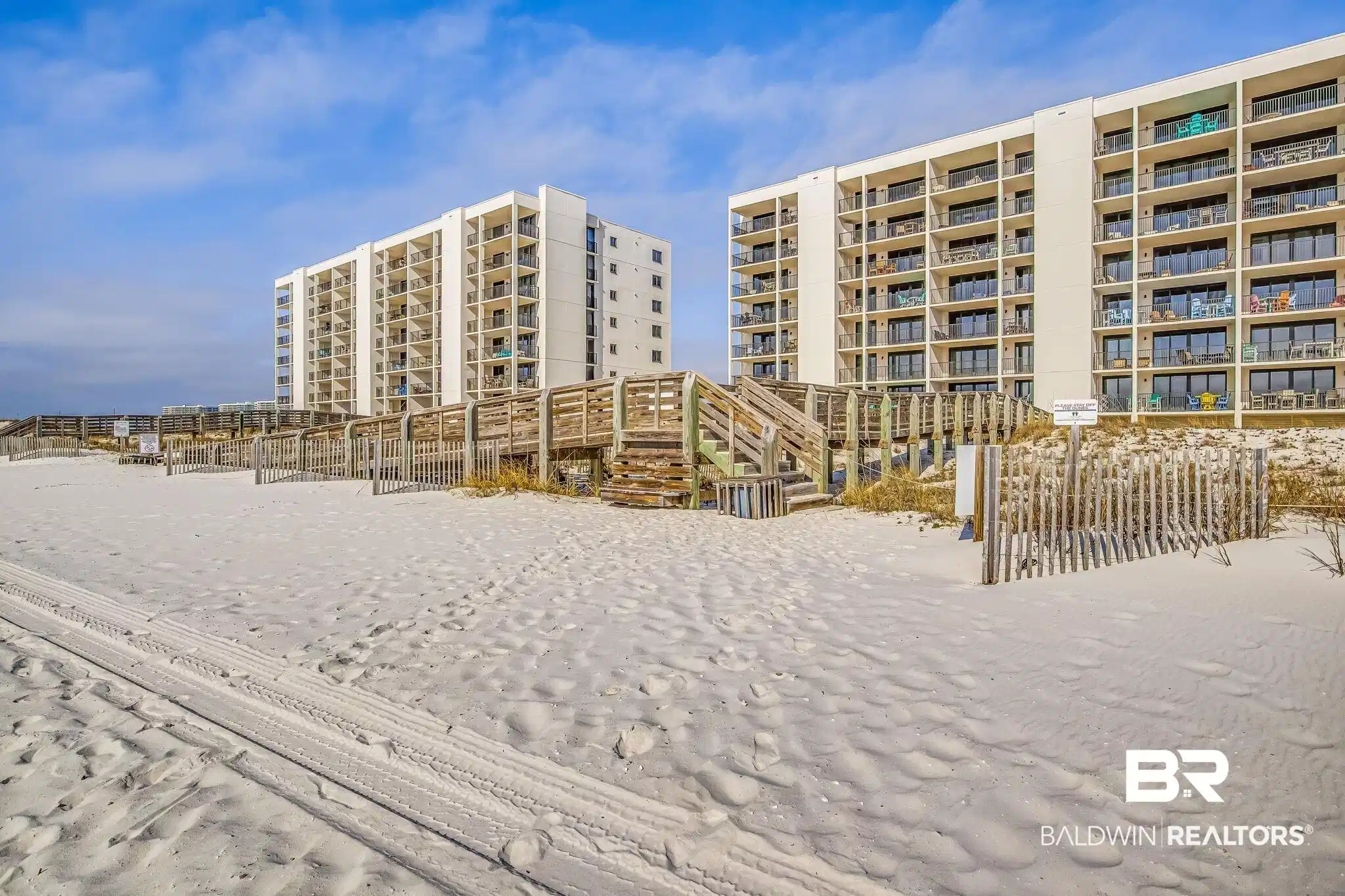 Image 1: White sand beach with direct boardwalk access to multi-story condominium buildings featuring private balconies
