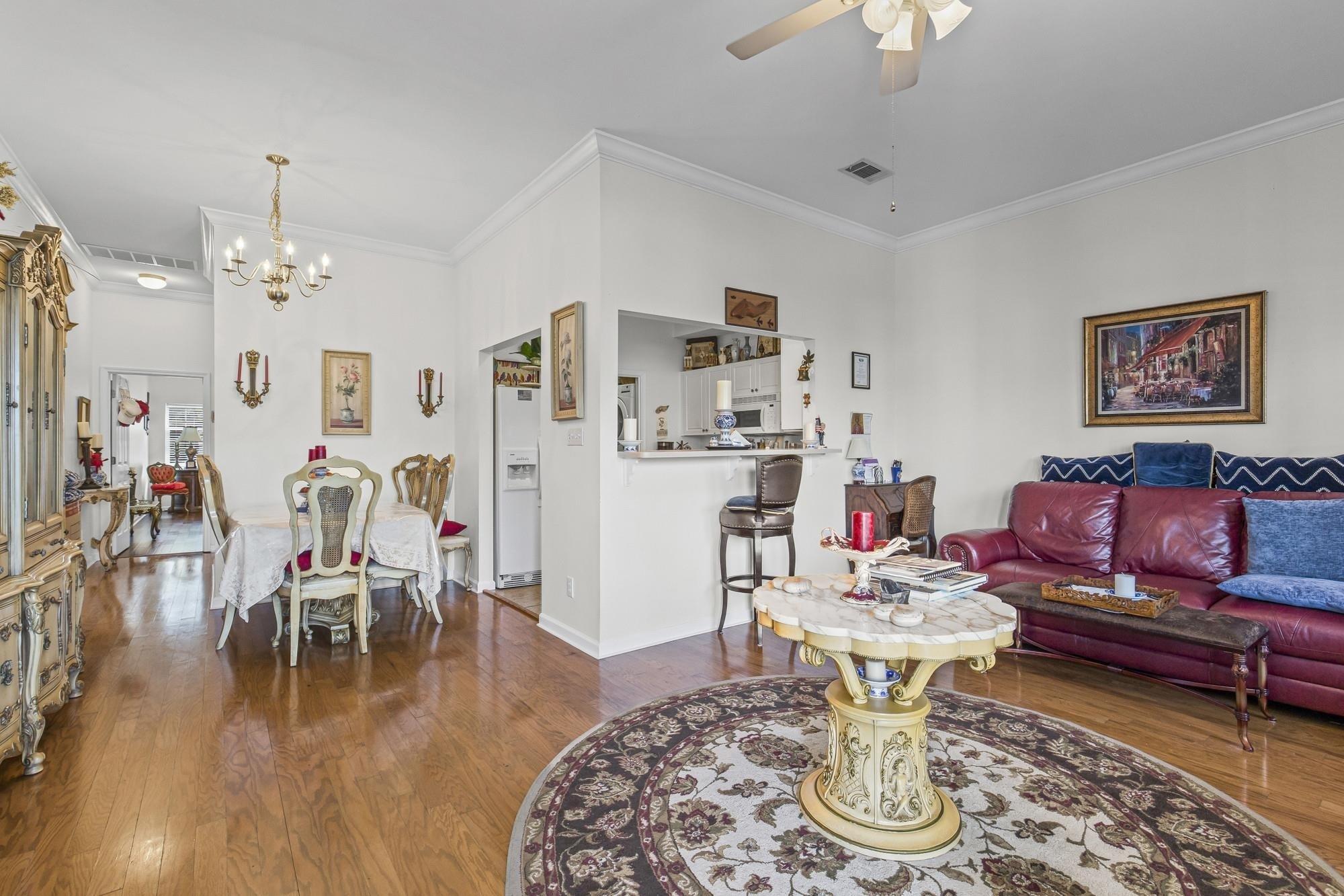 Image 4: Living room featuring crown molding, dark wood-type flooring, a chandelier, and a ceiling fan