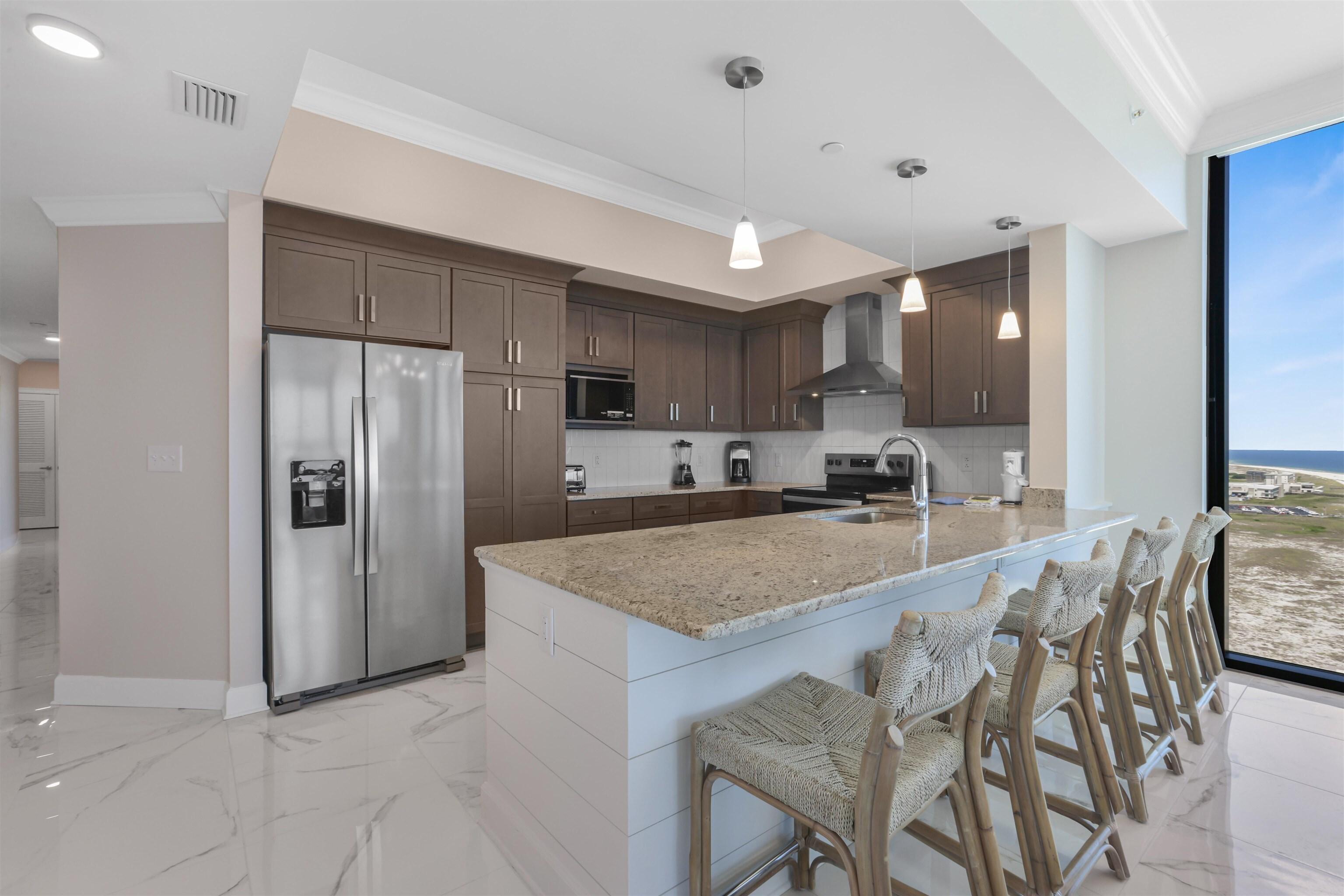Image 2: Kitchen with ornamental molding, dark brown cabinets, stainless steel appliances, backsplash, and pendant lighting
