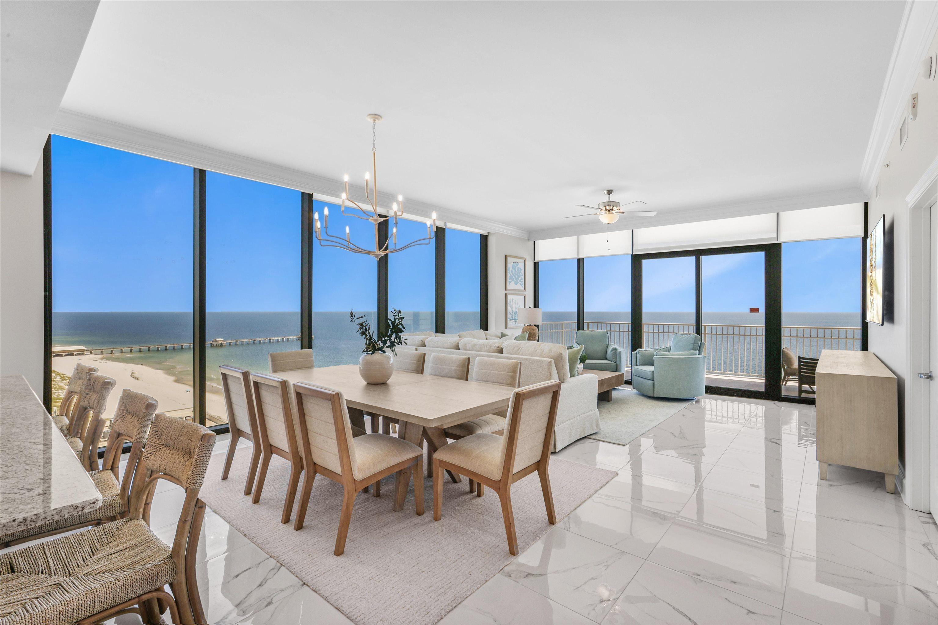 Image 4: Dining space with a wall of windows, view of water and beach, light marble finish flooring, a chandelier, and ornamental molding