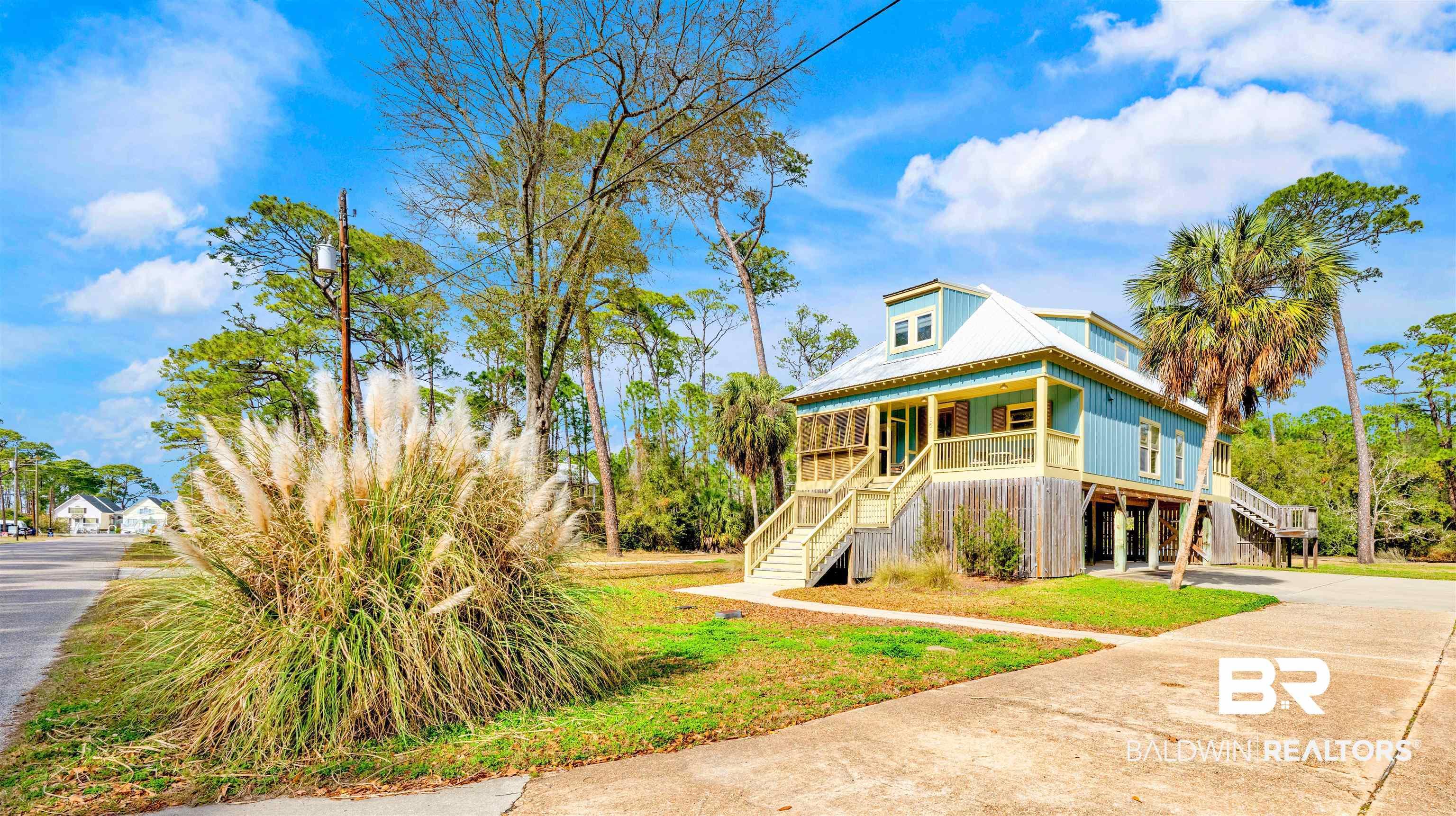 Image 1: Coastal home featuring covered porch, driveway, and a carport