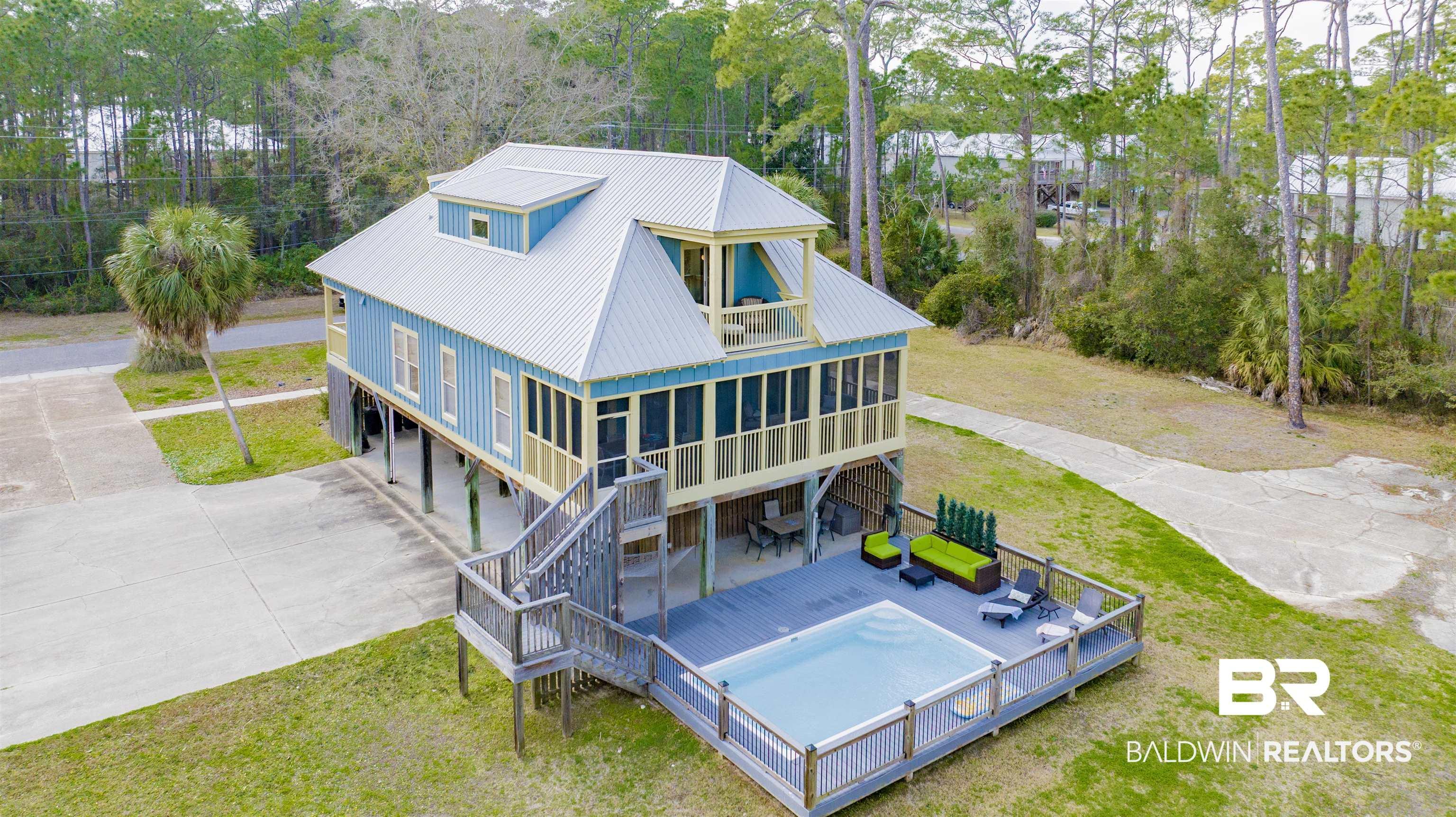 Image 3: Back of house with a wooden deck, a metal roof, a yard, a garage, and an outdoor pool
