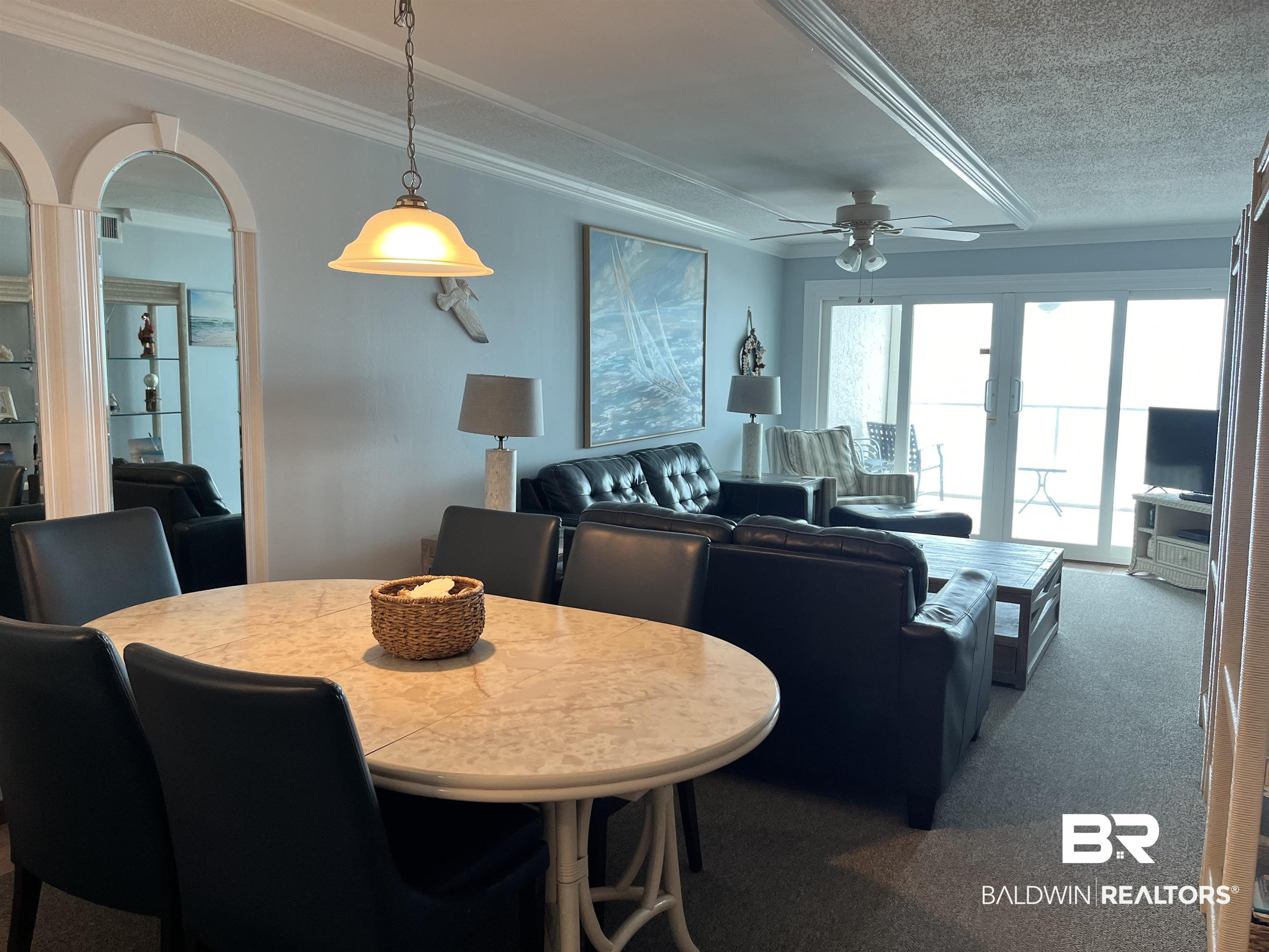 Image 4: Carpeted dining space with a textured ceiling, a ceiling fan, arched walkways, and crown molding