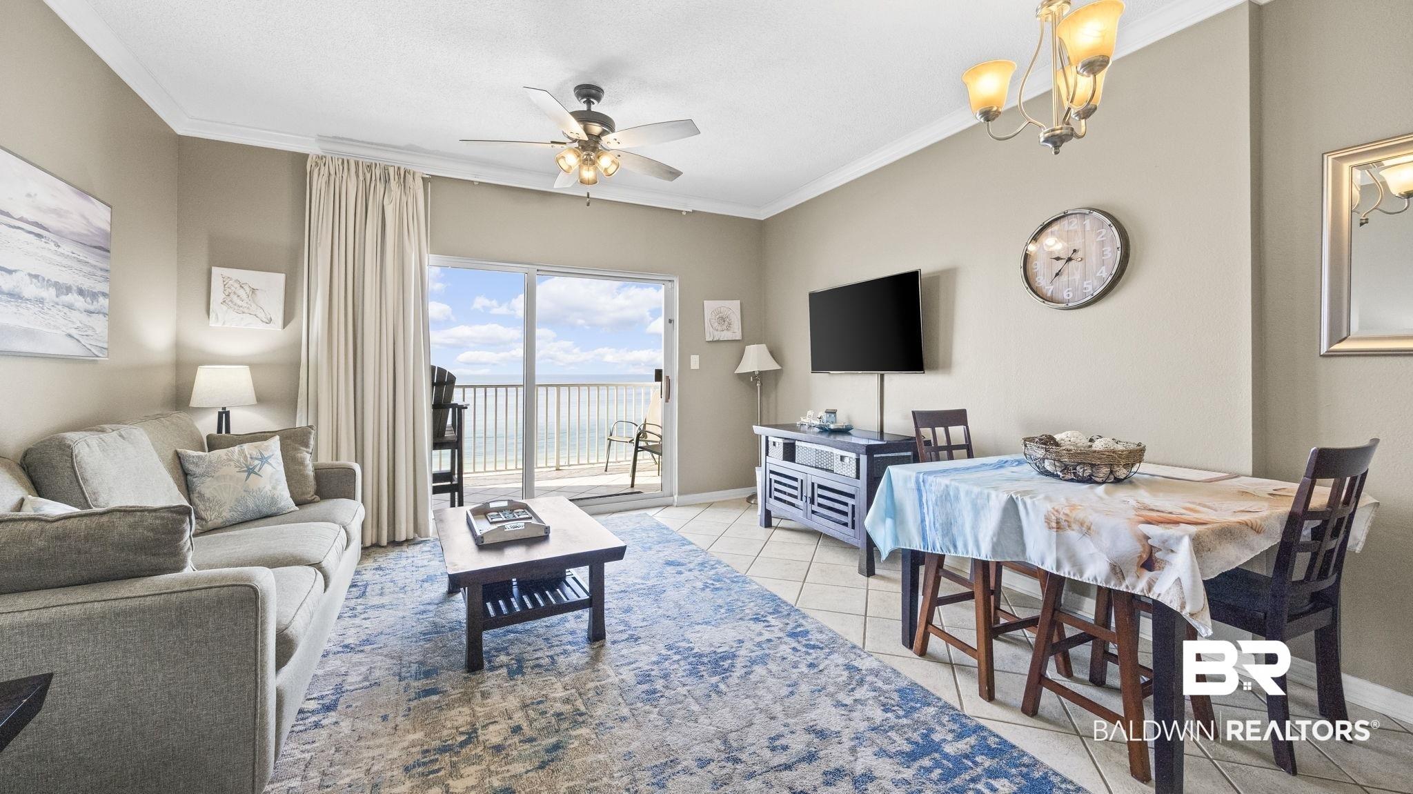 Image 3: Living room featuring crown molding, a ceiling fan, light tile patterned flooring, and a chandelier