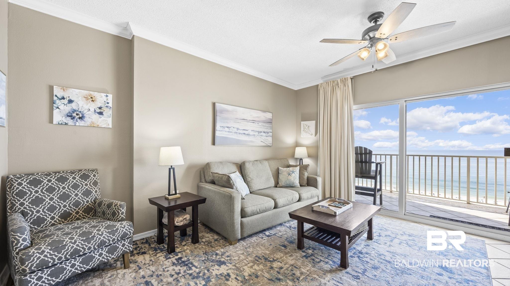 Image 4: Living area featuring view of water and beach, a ceiling fan, and ornamental molding