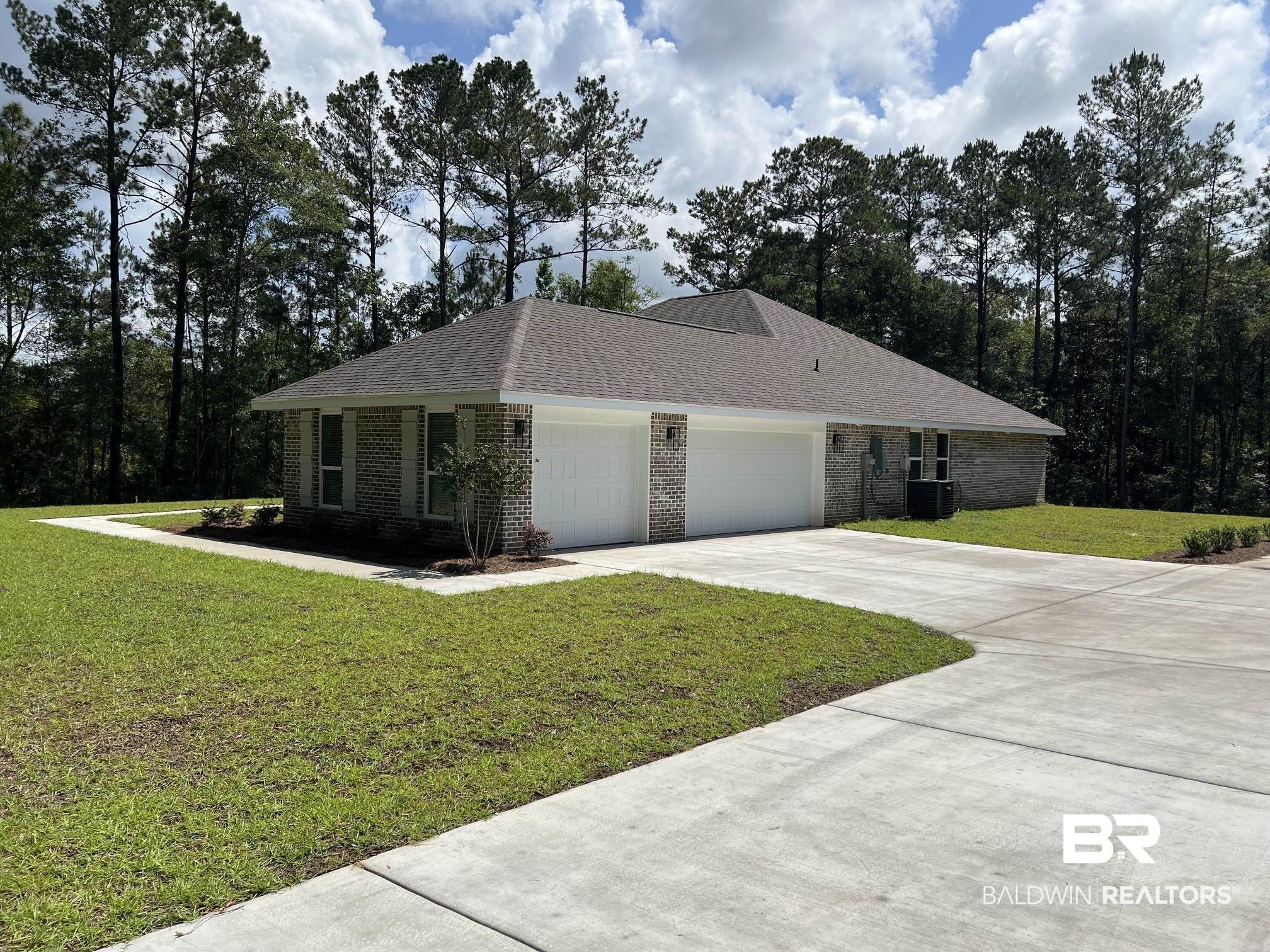 Image 2: Brick exterior with multiple garages, a concrete driveway, and mature tree-lined surroundings