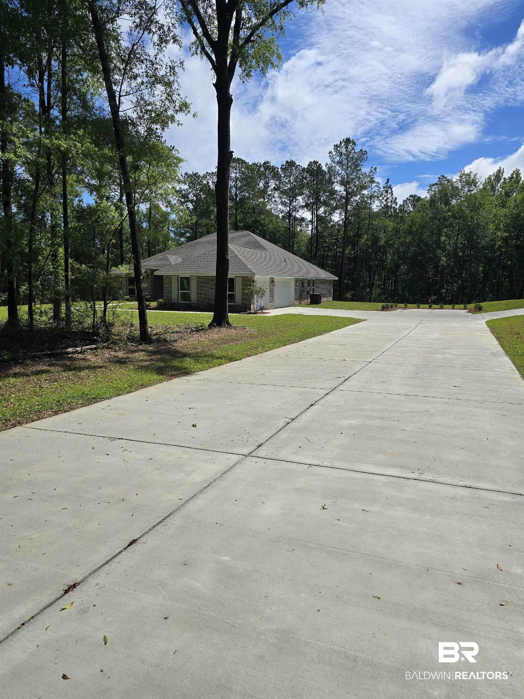 Image 3: Long concrete driveway with a split leading to a single-story residence