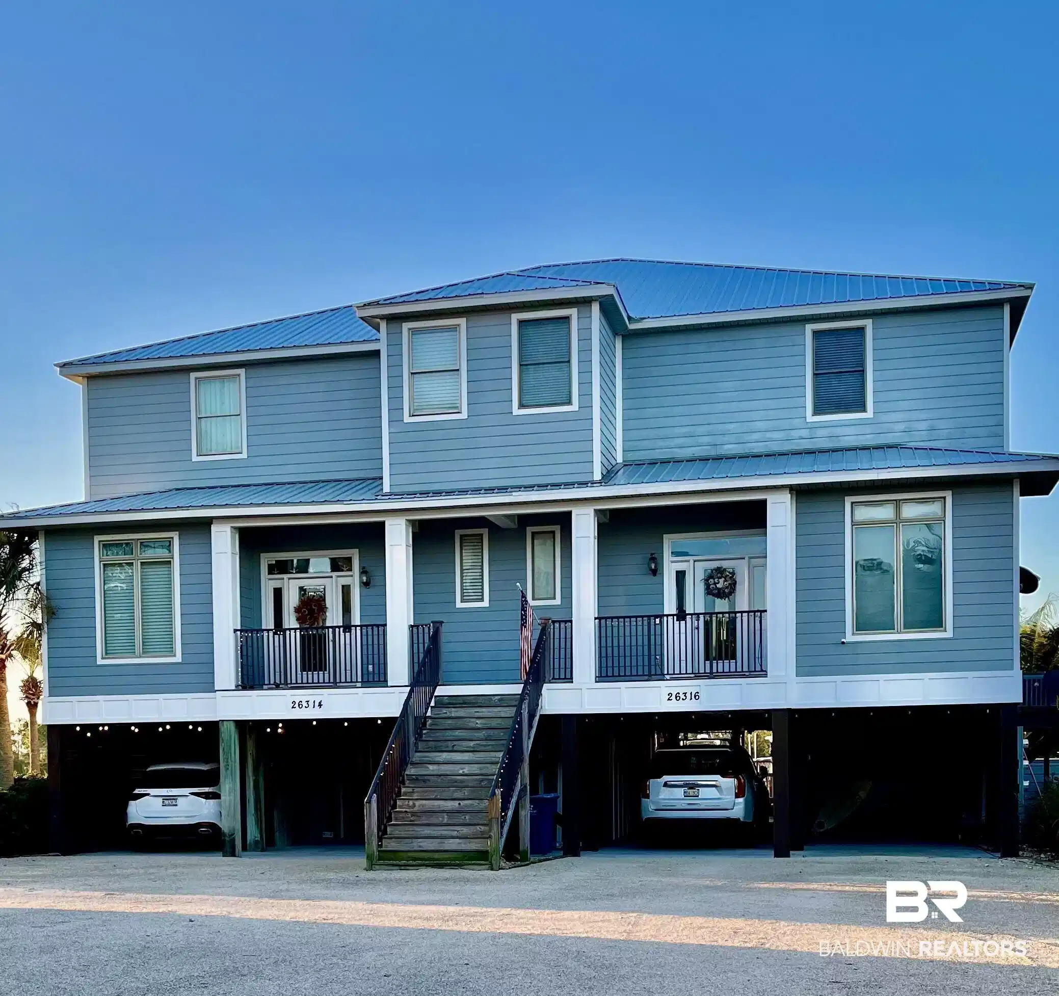 Image 1: Coastal inspired home with a carport, stairs, a metal roof, and a porch
