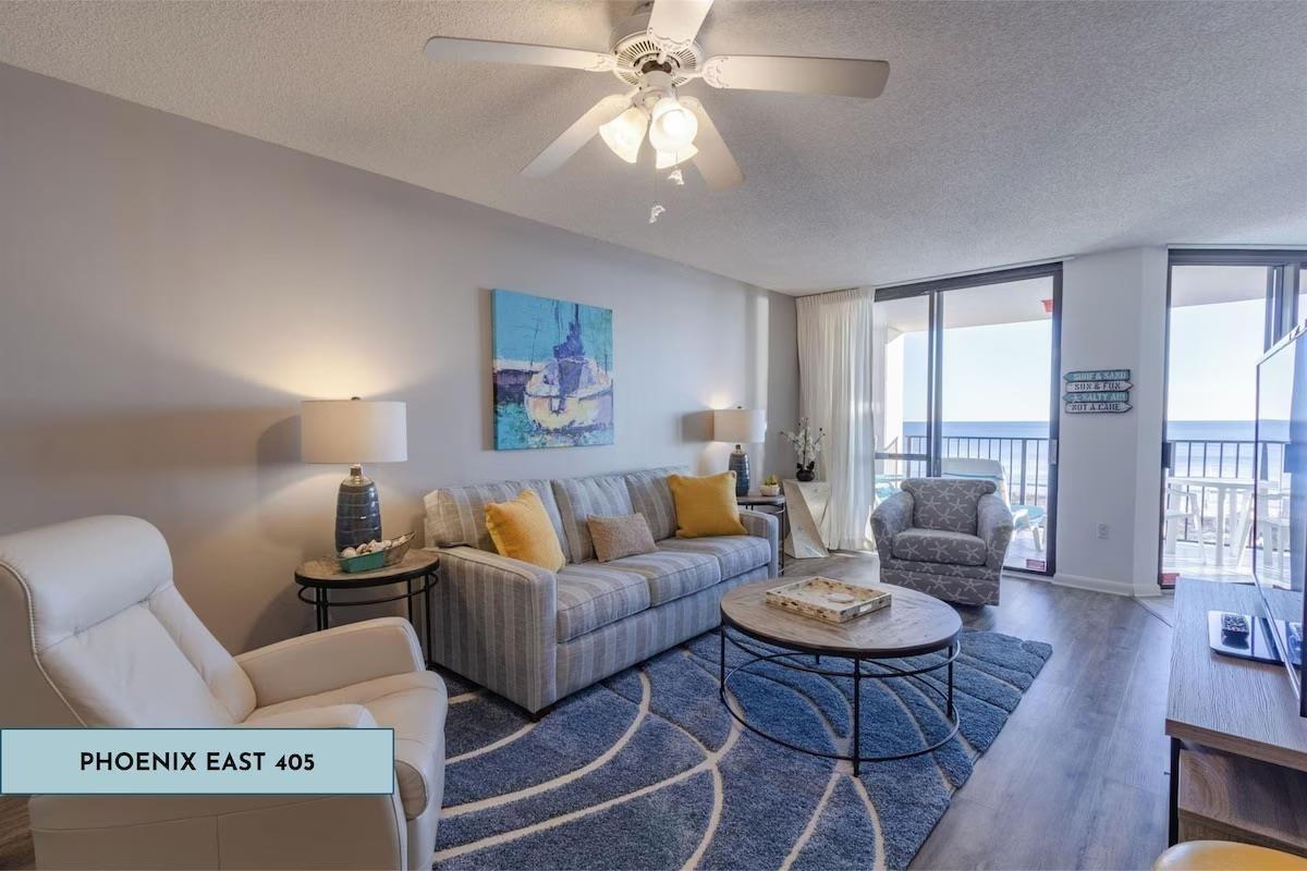 Image 2: Living room with a textured ceiling, wood finished floors, floor to ceiling windows, and ceiling fan