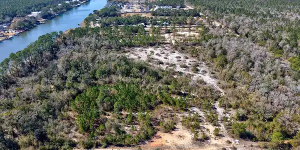 Image 4: Aerial view of property and surrounding area with a forest and a nearby body of water