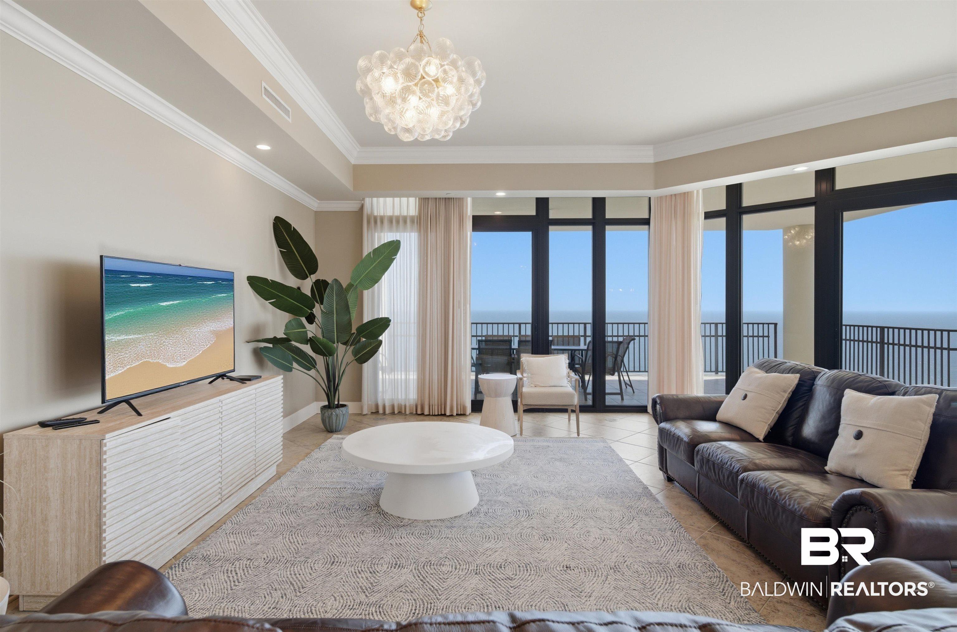 Image 2: Living area featuring a water view, hanging lights, crown molding, and light tile patterned floors