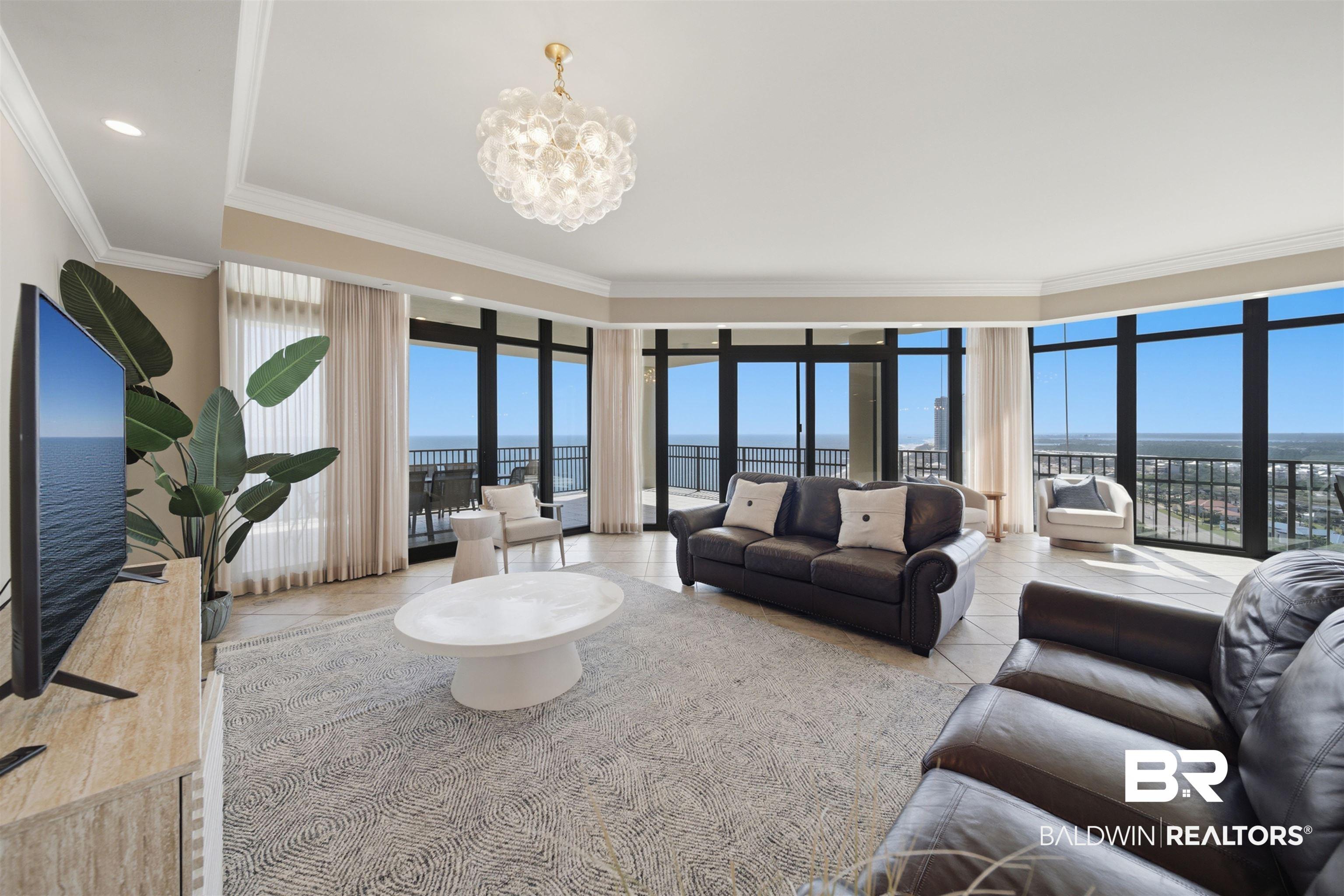 Image 3: Living room with suspended lighting, a water view, ornamental molding, light tile patterned flooring, and expansive windows
