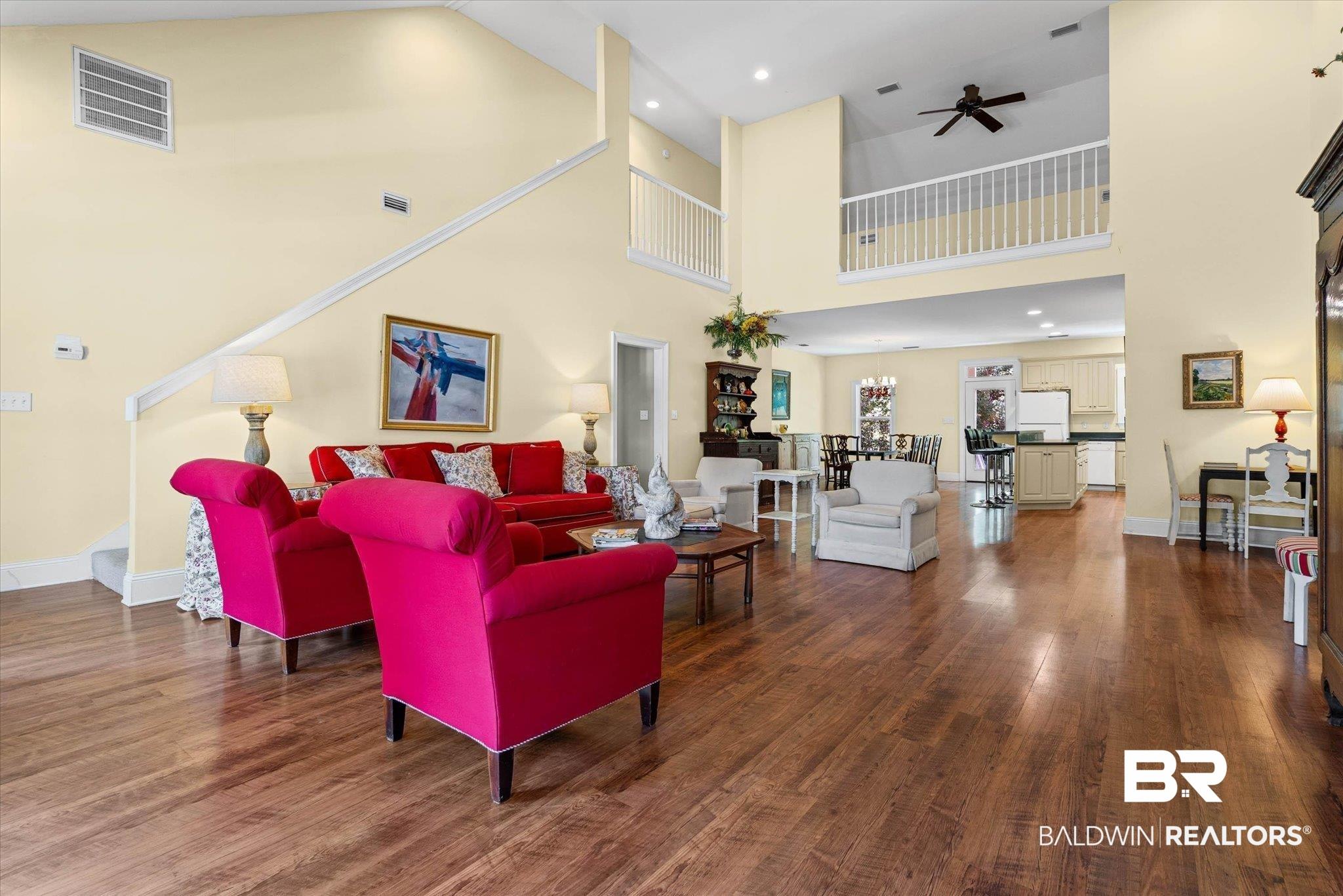 Image 3: Spacious living area featuring high ceilings, wood-finish flooring, and a second-story balcony overlook