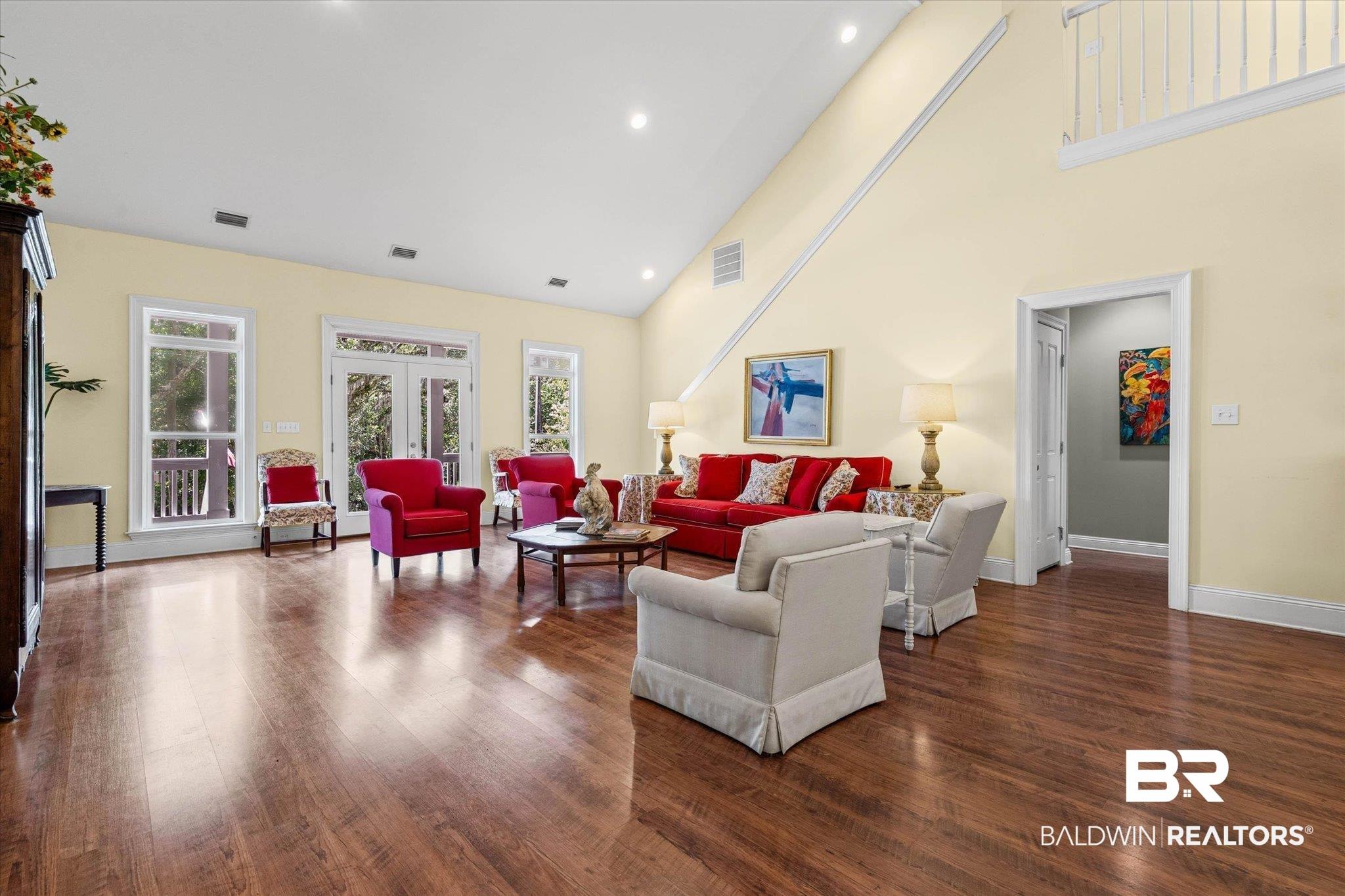Image 4: Spacious living area featuring high vaulted ceilings, recessed lighting, wood-finish flooring, and multiple French doors with transom windows