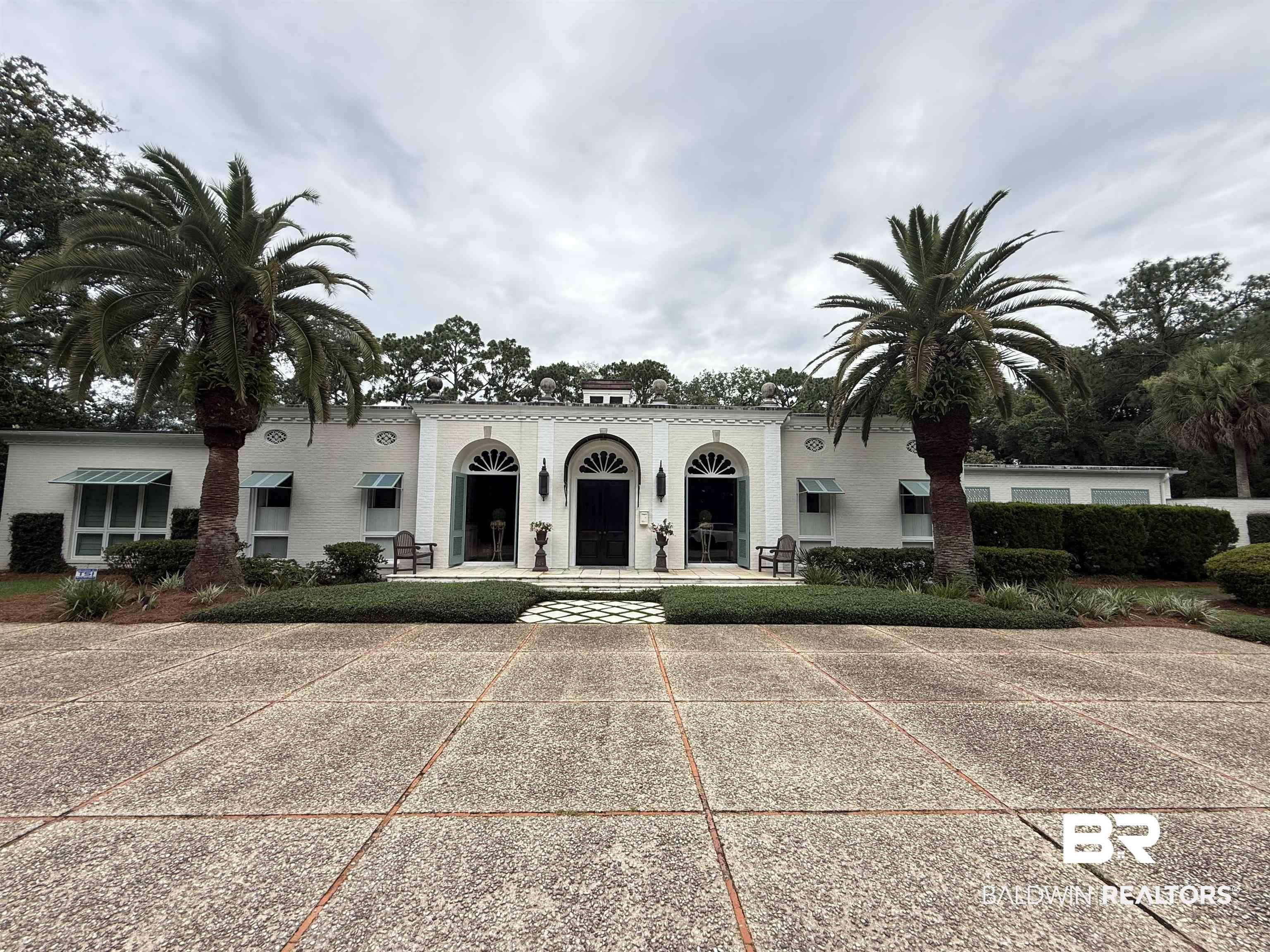Image 3: Expansive concrete motor court featuring a manicured shrub border and two mature palm trees