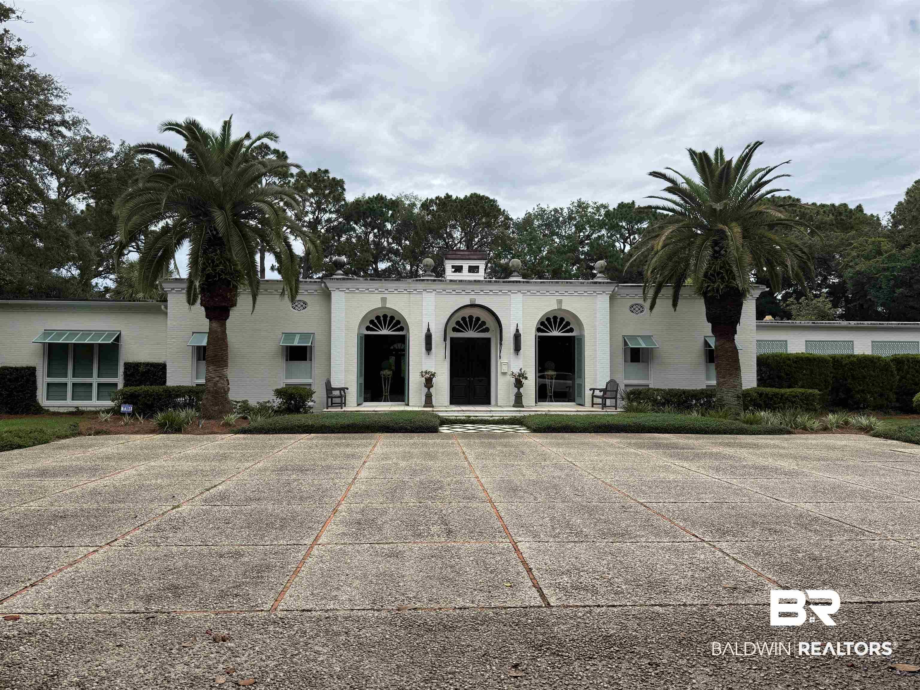 Image 4: Elegant white stucco exterior featuring arched entryways and a central decorative pediment