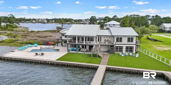 Image 3: Waterfront property featuring a private dock, an in-ground swimming pool, and an expansive paved patio