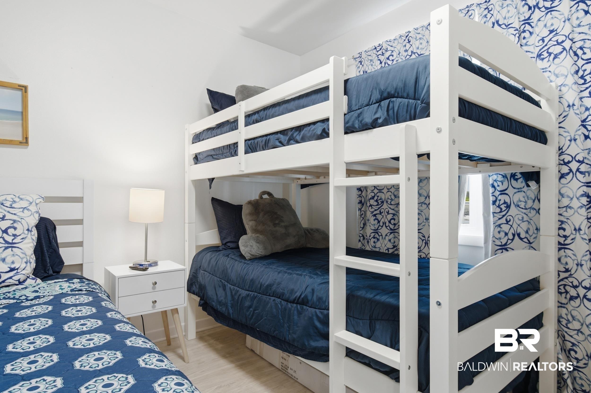 Image 4: White bunk bed with integrated ladder, white walls, light wood-finish flooring, and patterned window treatments