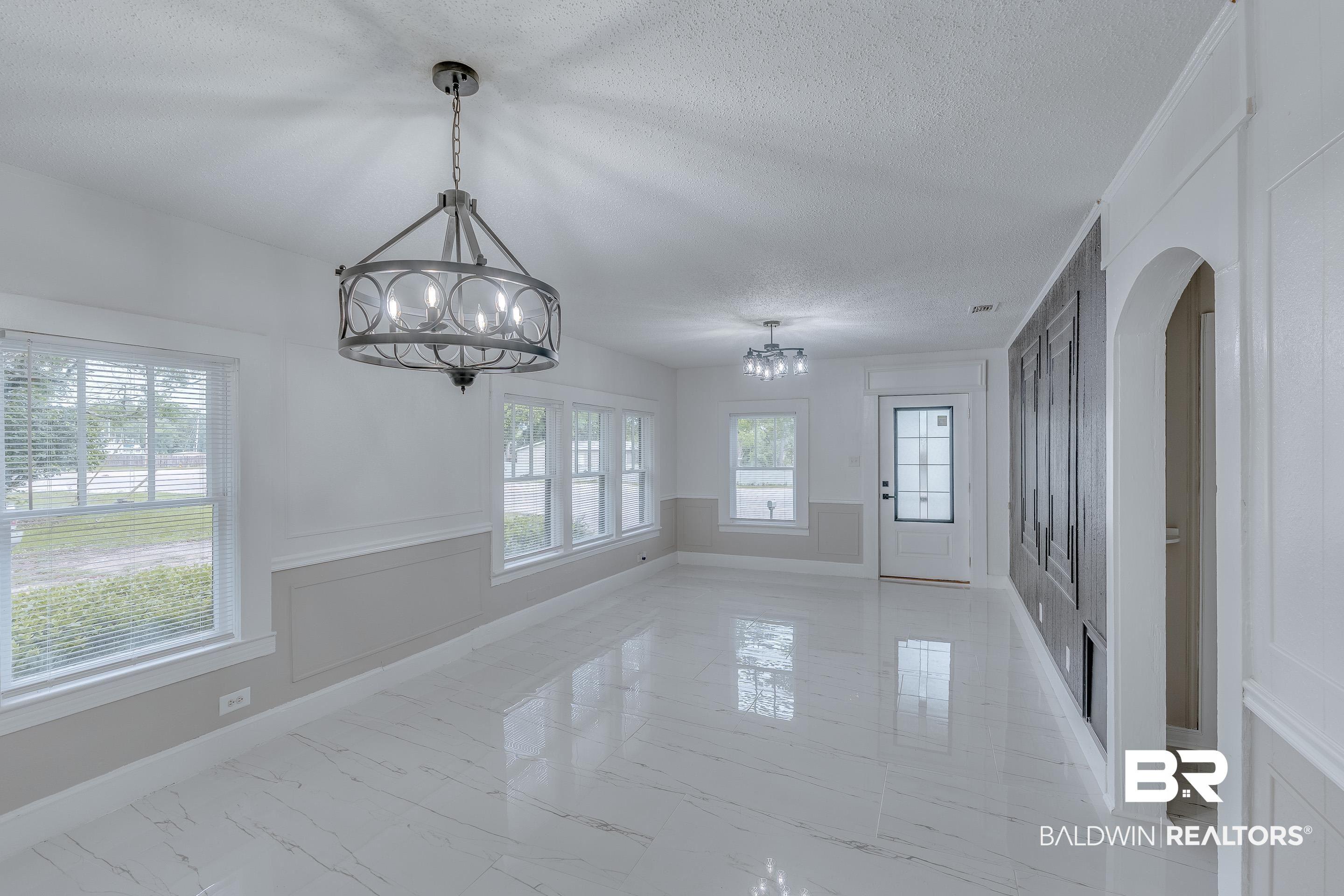 Image 3: Unfurnished dining area with a textured ceiling, light marble finish flooring, and a chandelier