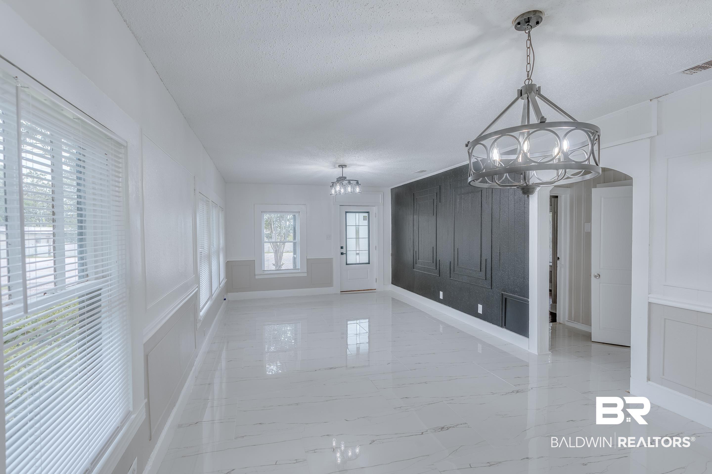 Image 4: Unfurnished dining area with a decorative wall, light marble finish flooring, a chandelier, a textured ceiling, and arched walkways
