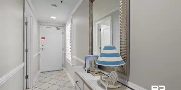 Image 3: Entryway featuring diamond-patterned floor tiling, an accent mirror, and a built-in console table with cabinet storage