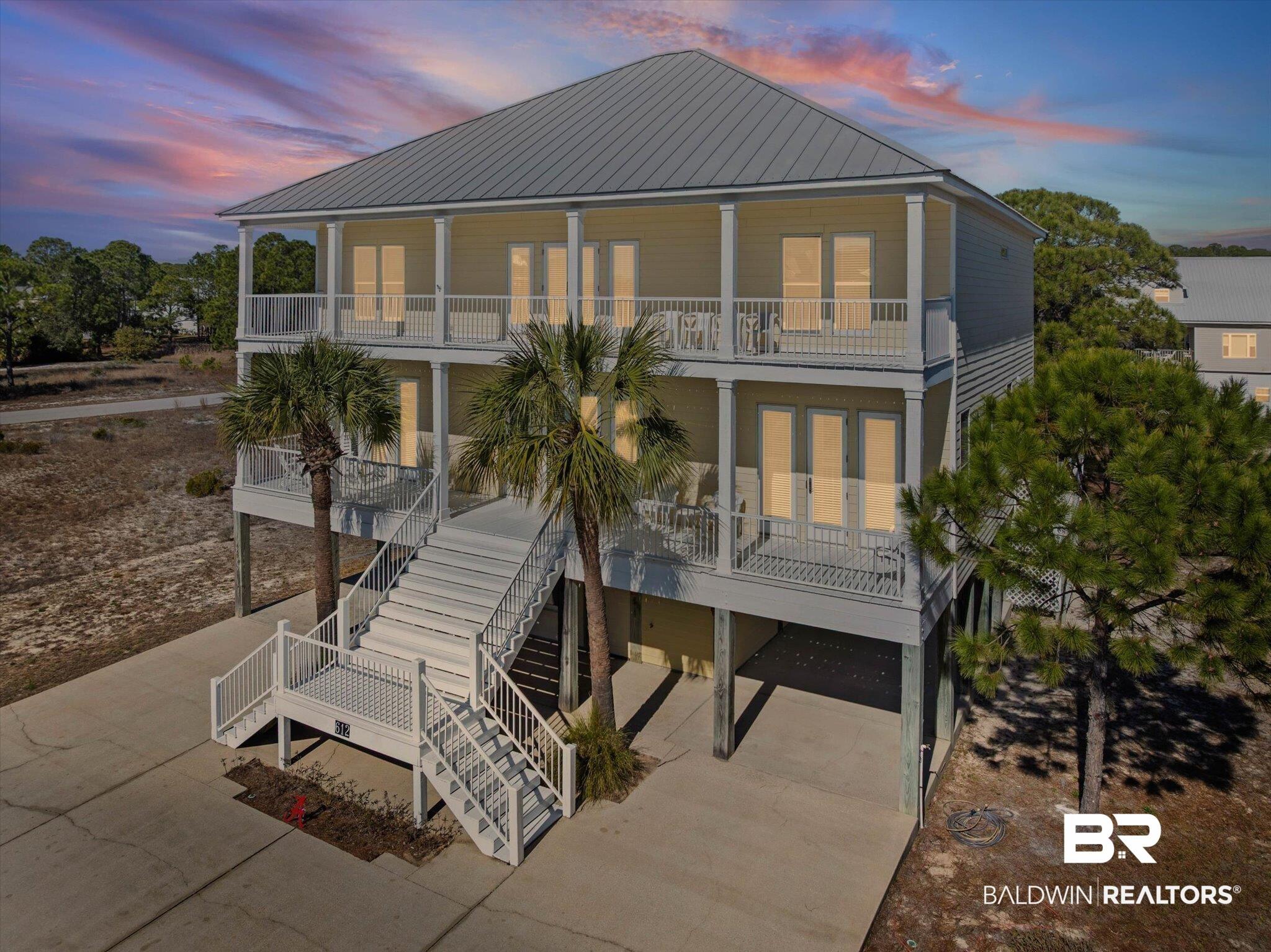 Image 1: Rear view of property featuring a carport, stairway, a porch, driveway, and a metal roof