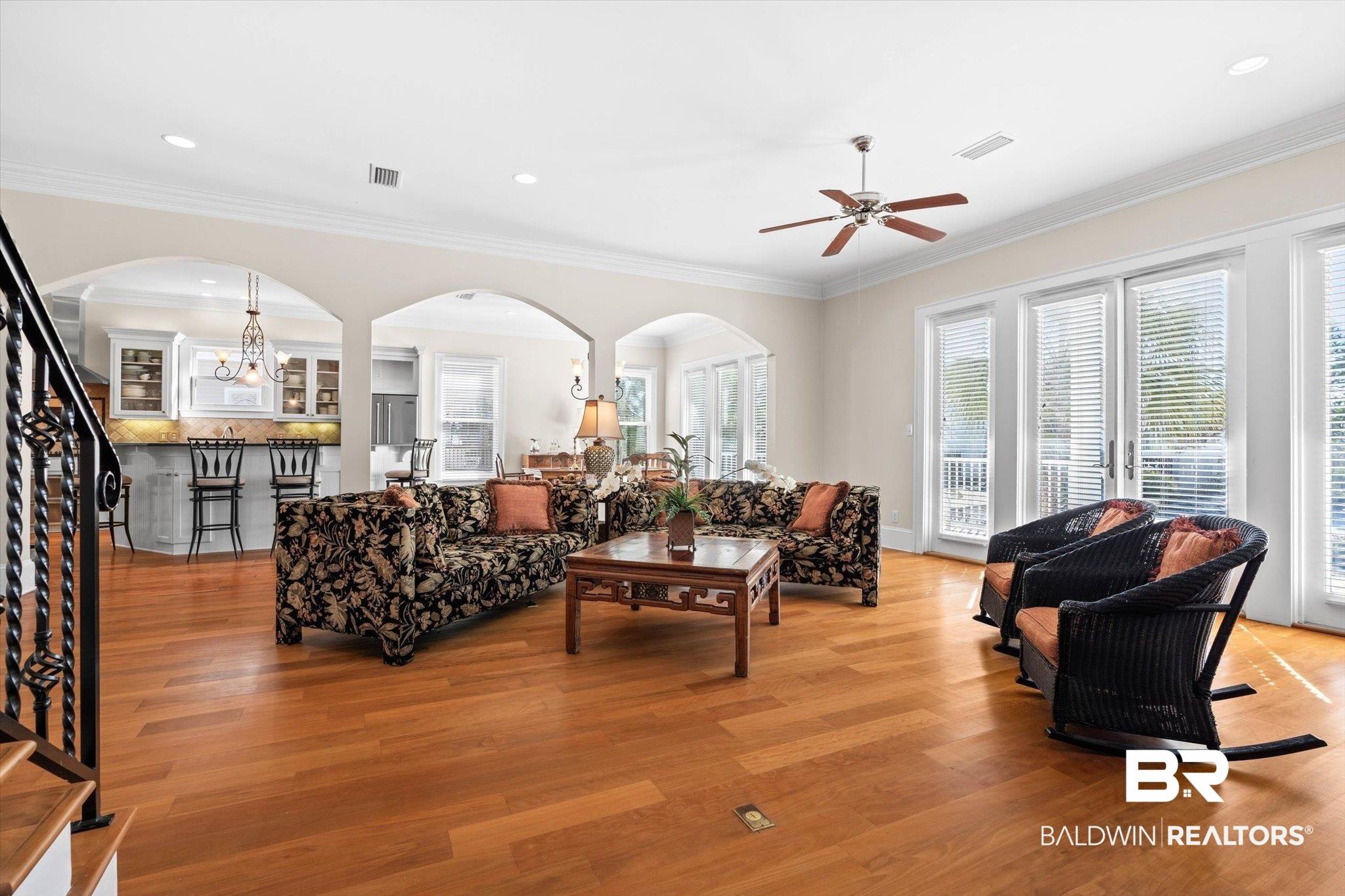 Image 3: Living room with crown molding, stairs, light wood-style floors, recessed lighting, and arched walkways