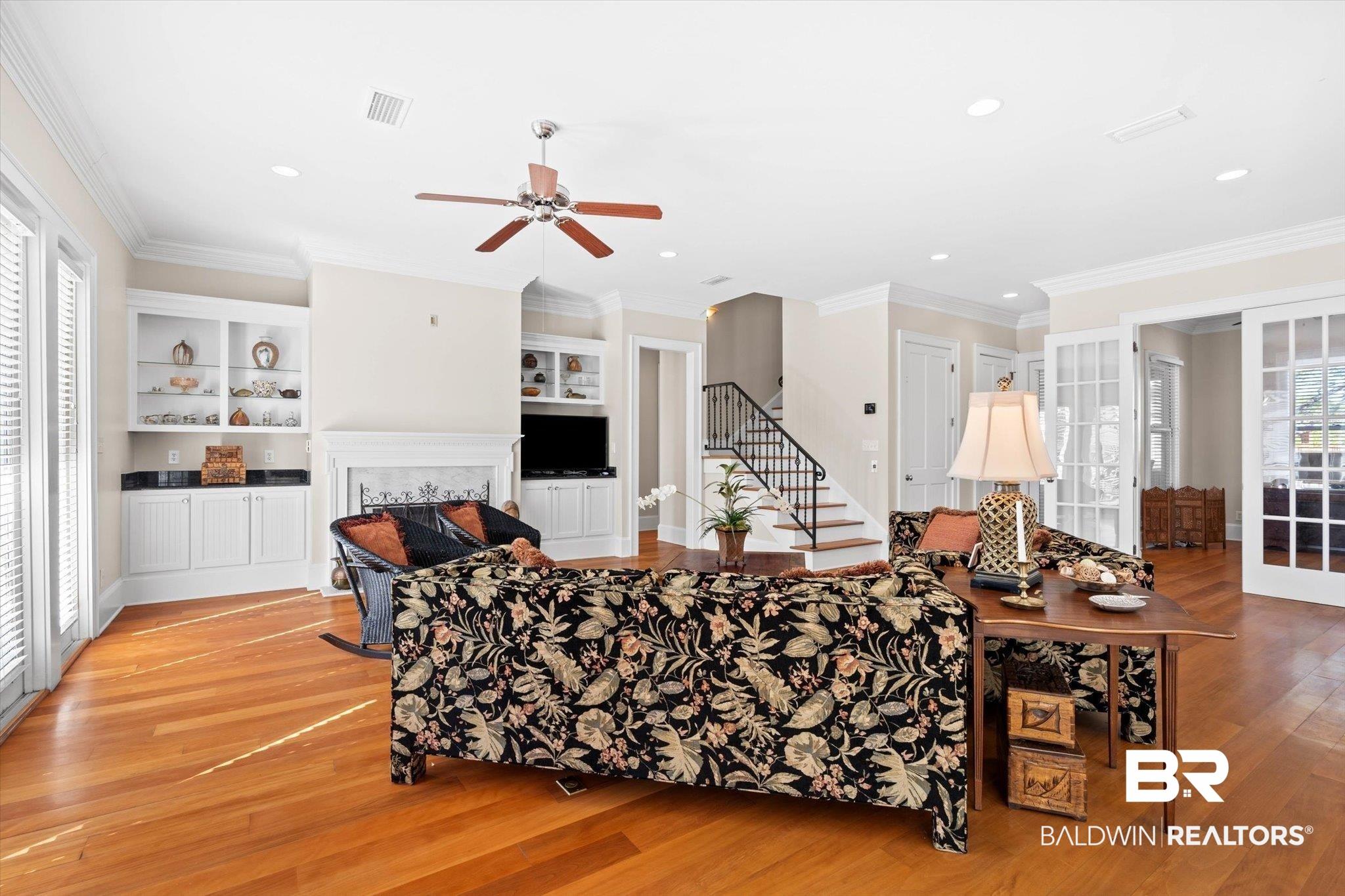 Image 4: Living room with crown molding, stairway, built in features, wood-type flooring, and ceiling fan