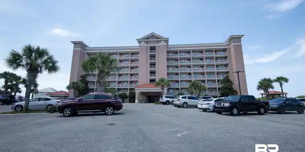 Image 3: Multi-story building featuring numerous balconies and a central entrance portico with a red tile roof