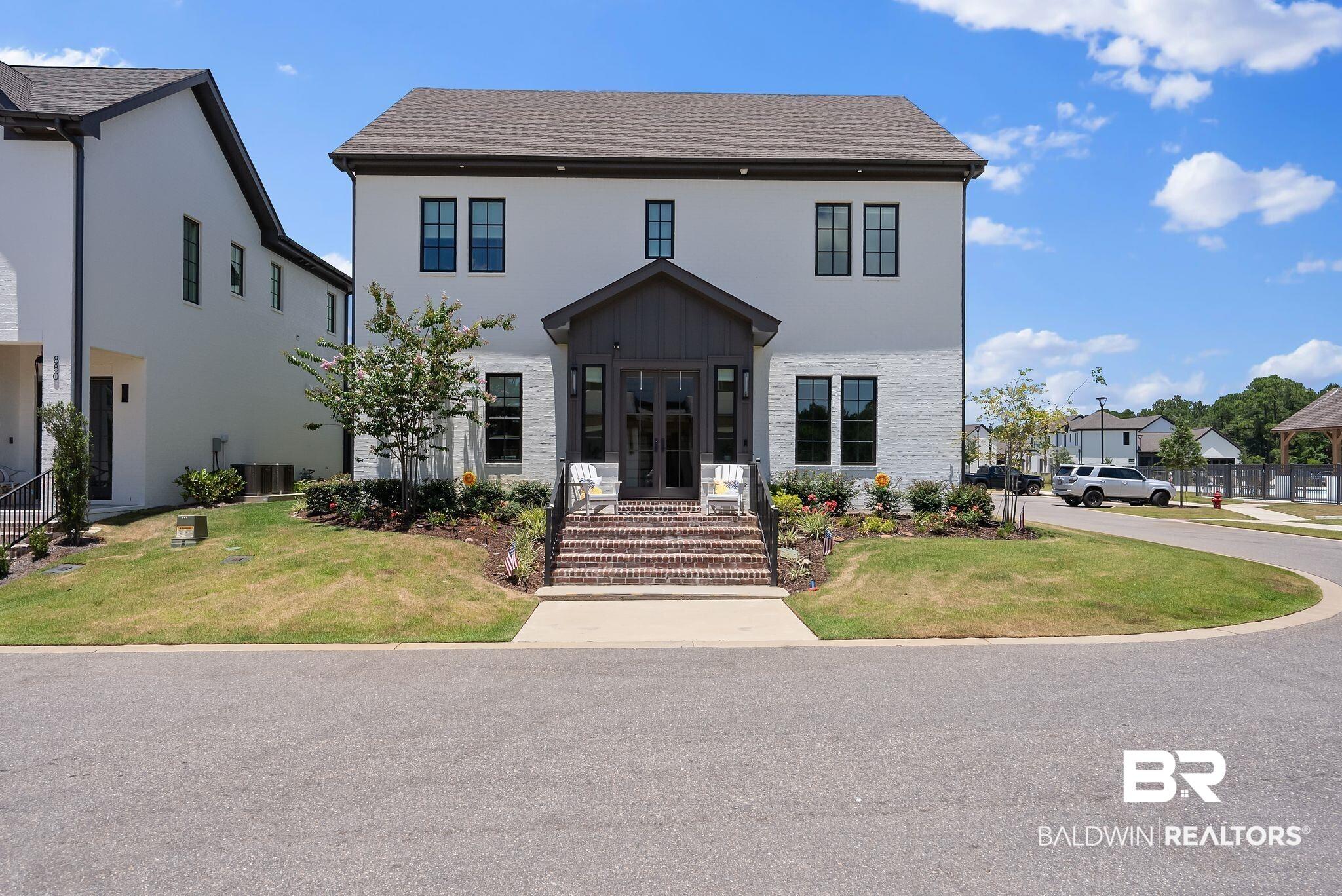 Image 2: Contemporary two-story residence featuring a white brick exterior with dark trim windows