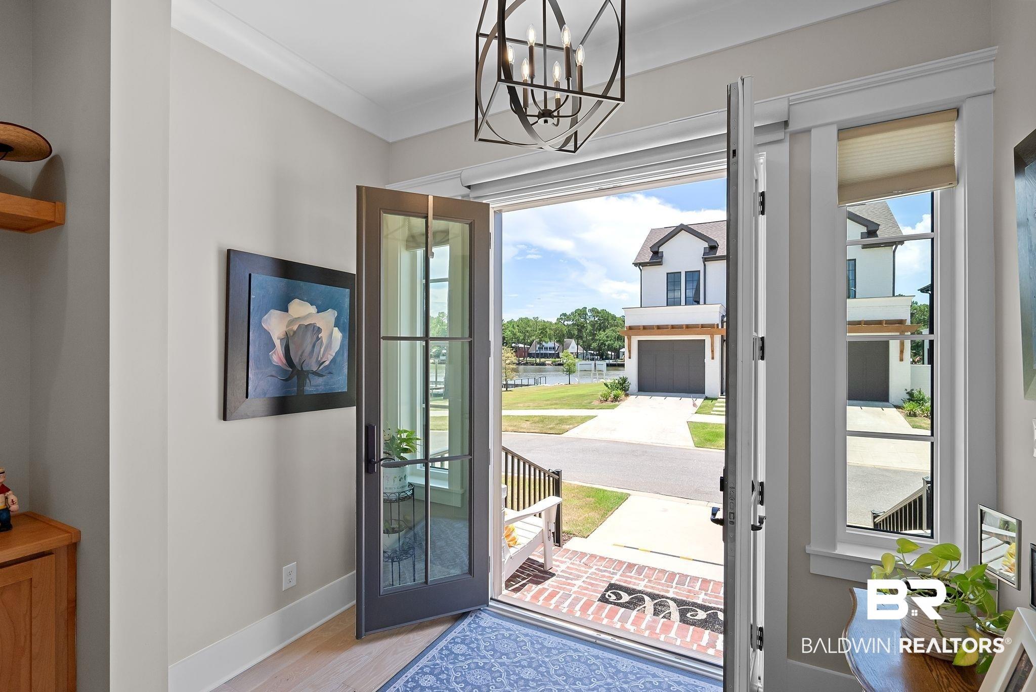 Image 3: Entryway featuring French doors with transom windows, crown molding, and light wood-finish flooring