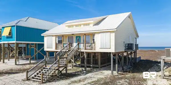 Image 2: Rear view of house featuring stairway, a metal roof, and a carport