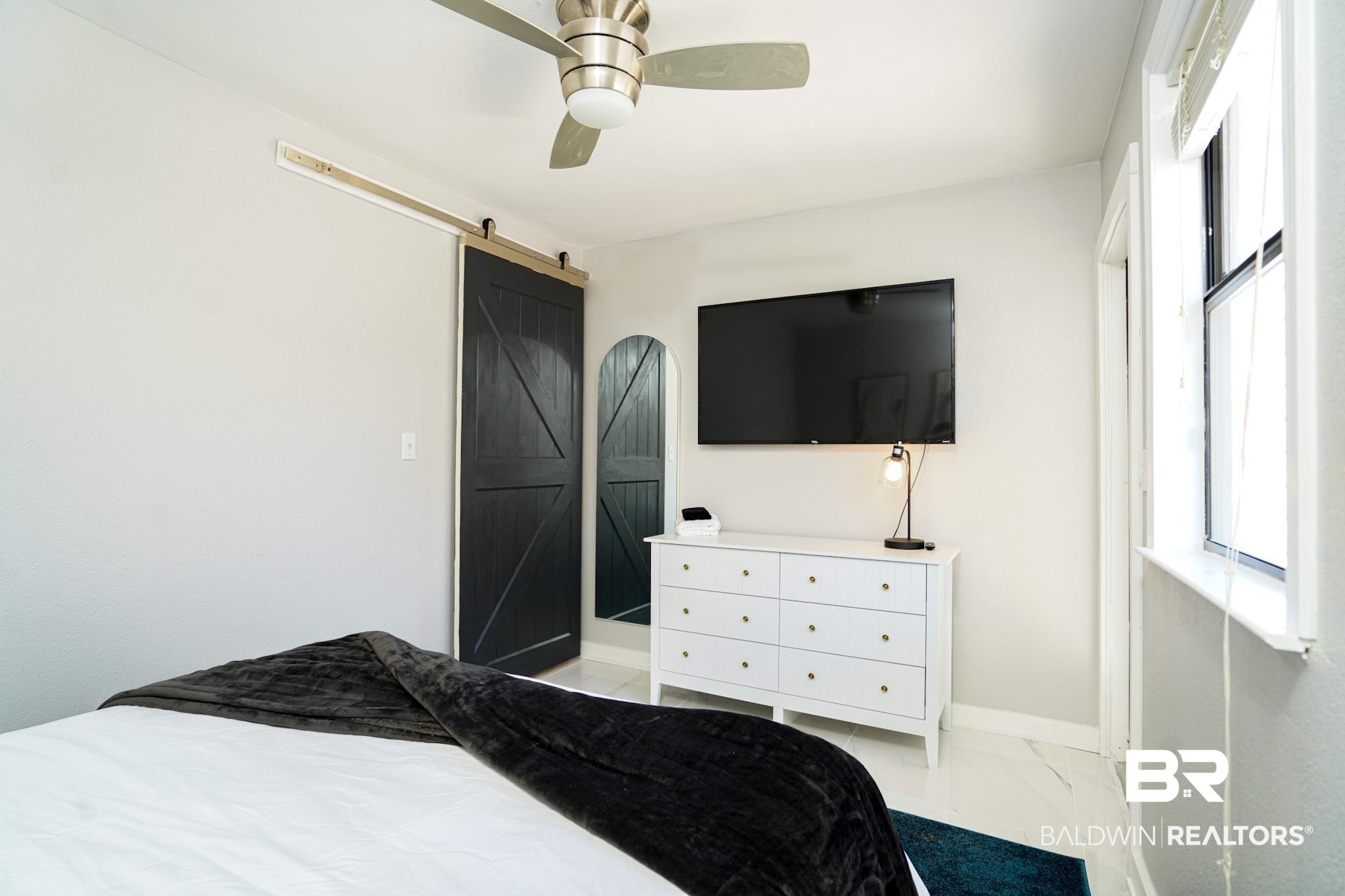 Image 4: Bedroom featuring a barn door and ceiling fan