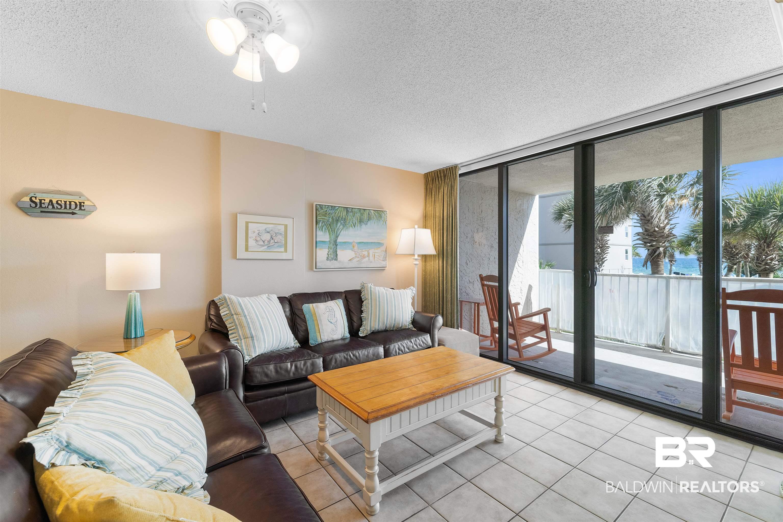 Image 4: Tiled living room with floor to ceiling windows and a textured ceiling