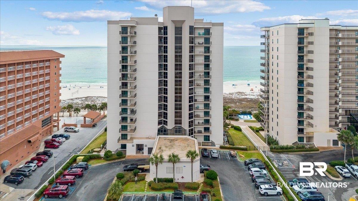 Image 2: View of apartment building / complex featuring view of water and beach and uncovered parking
