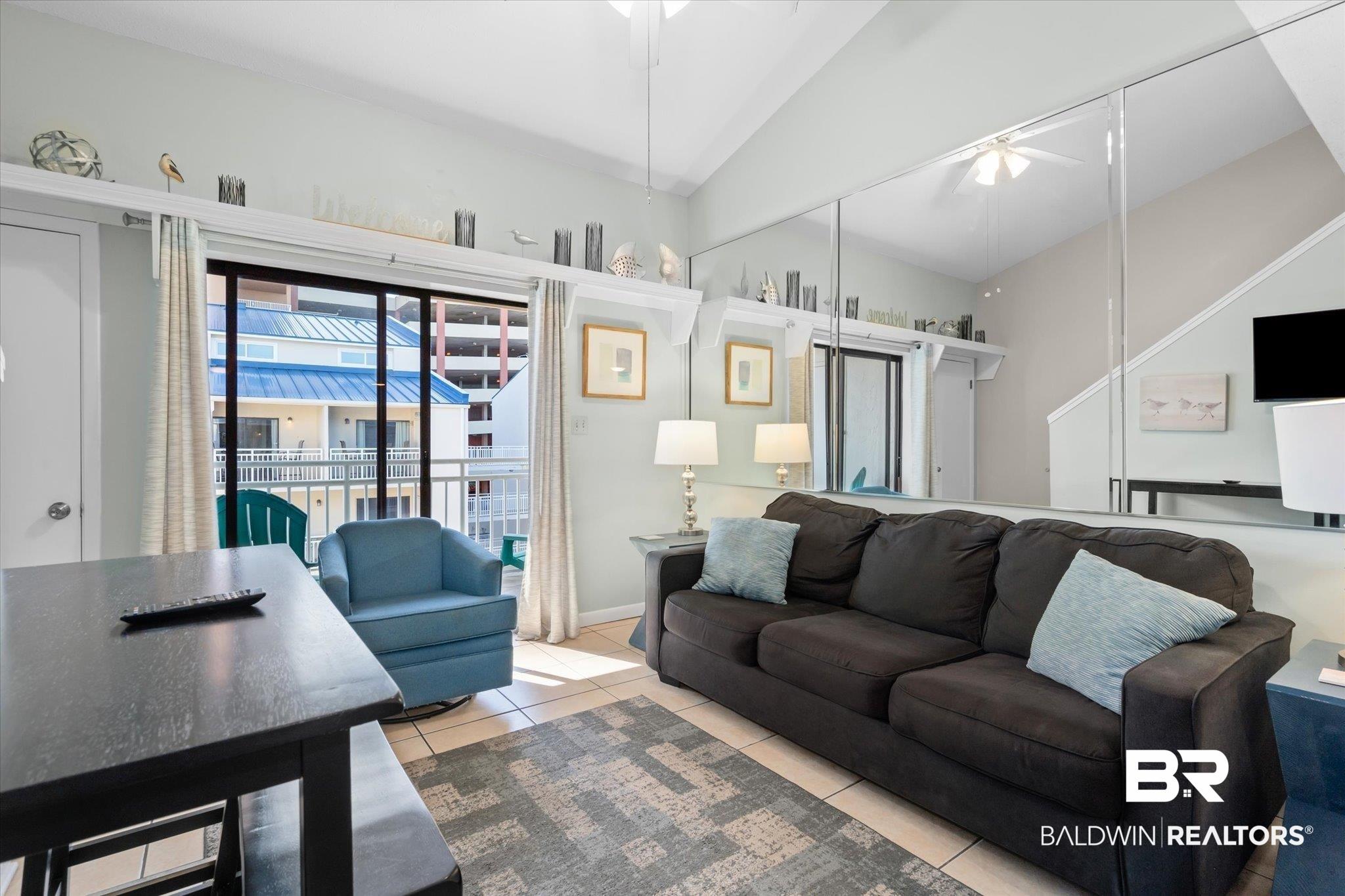 Image 4: Living room with a ceiling fan, tile patterned flooring, and lofted ceiling