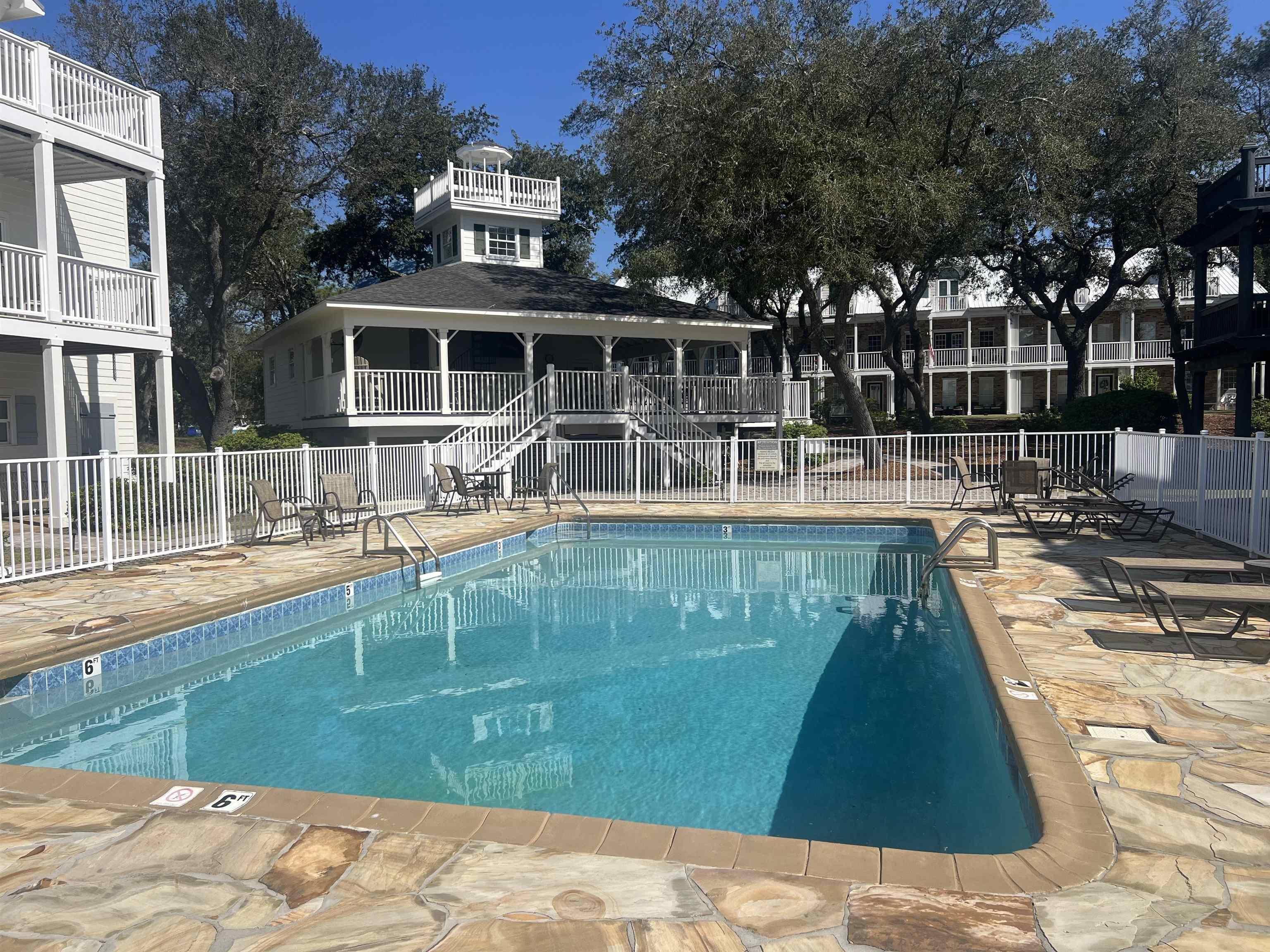 Image 2: Community pool with a patio and fence