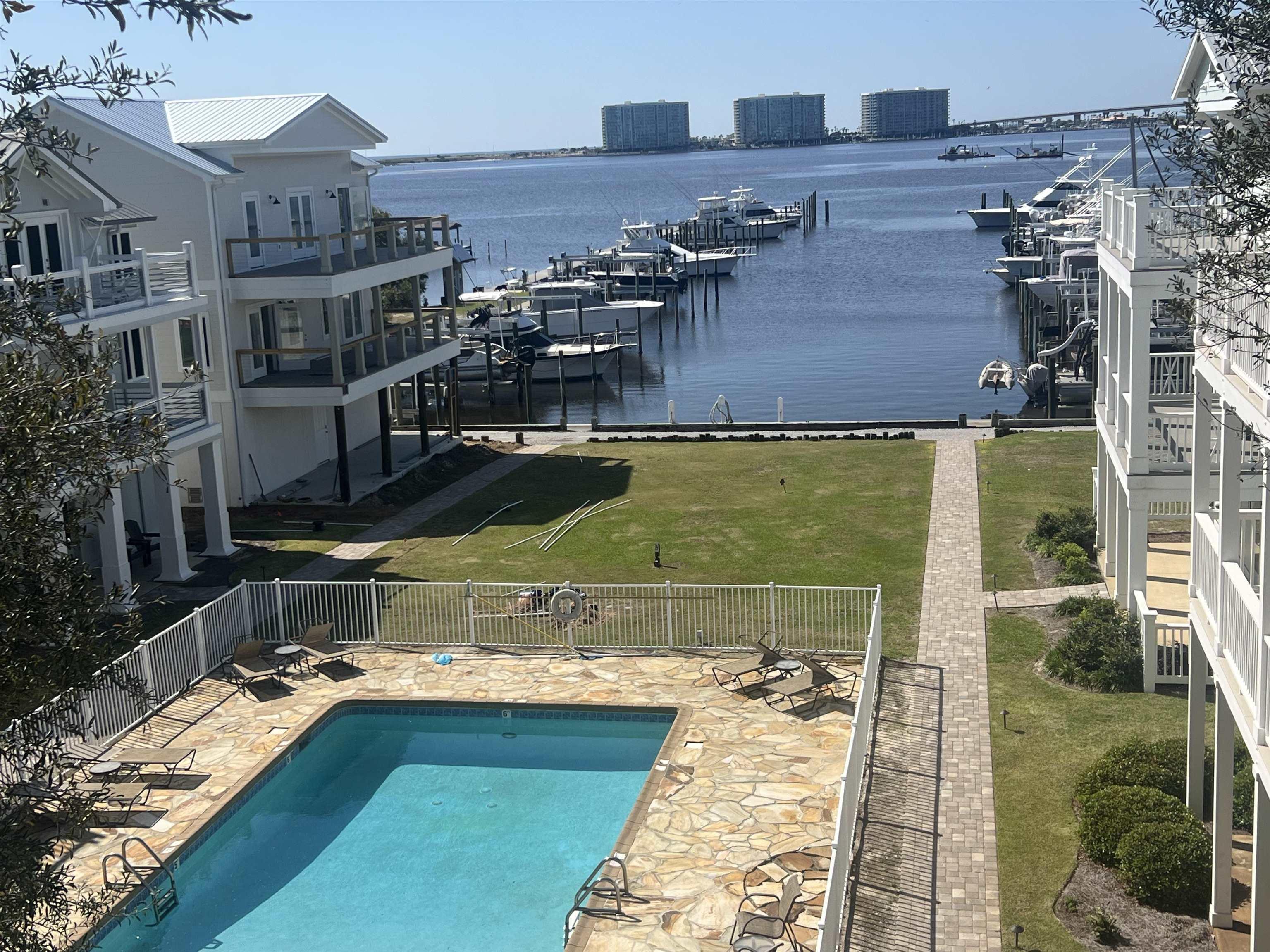 Image 3: Community pool with a patio area, fence, and a water view