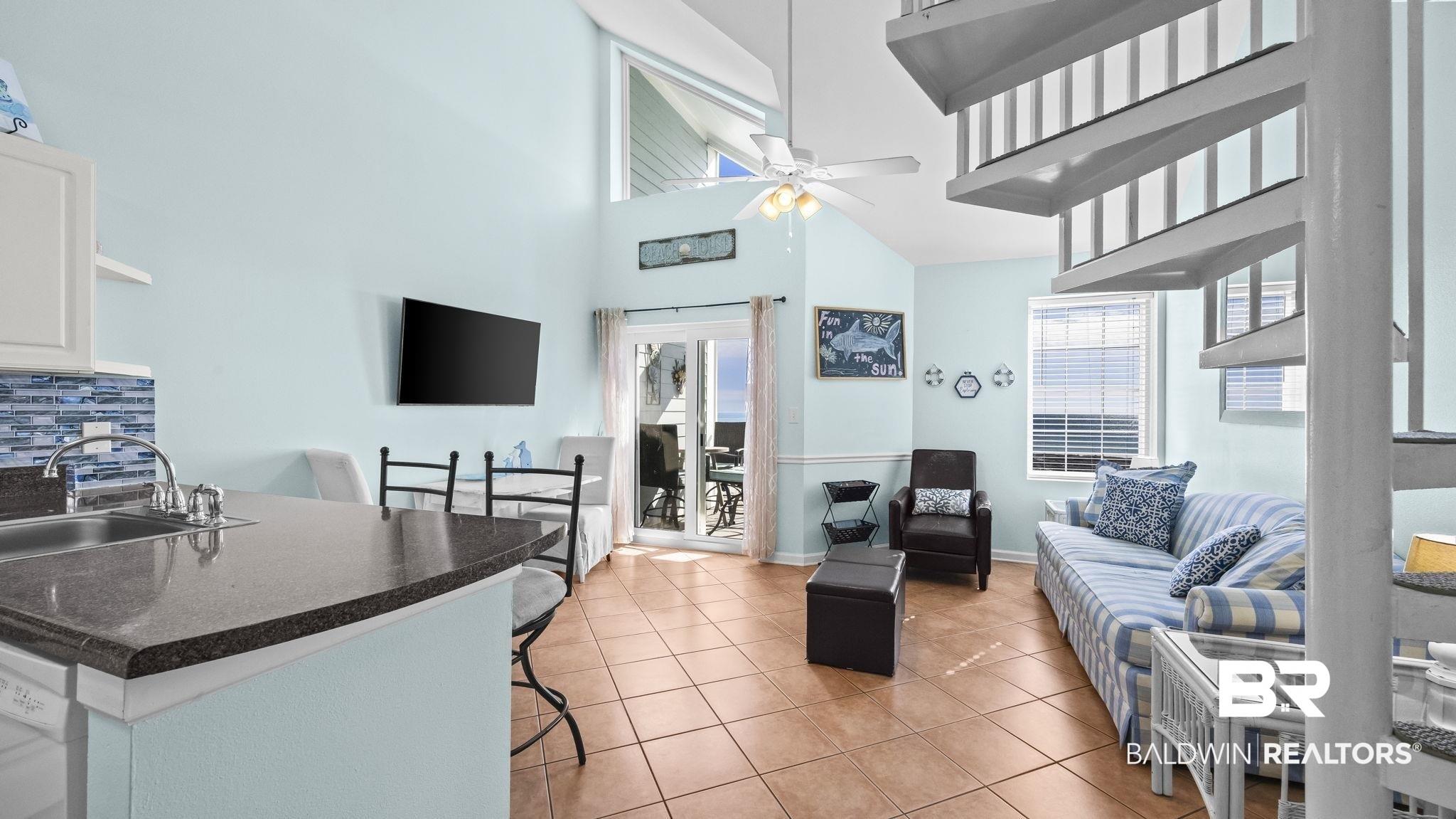 Image 4: Living area with light tile patterned floors, a ceiling fan, and a high ceiling