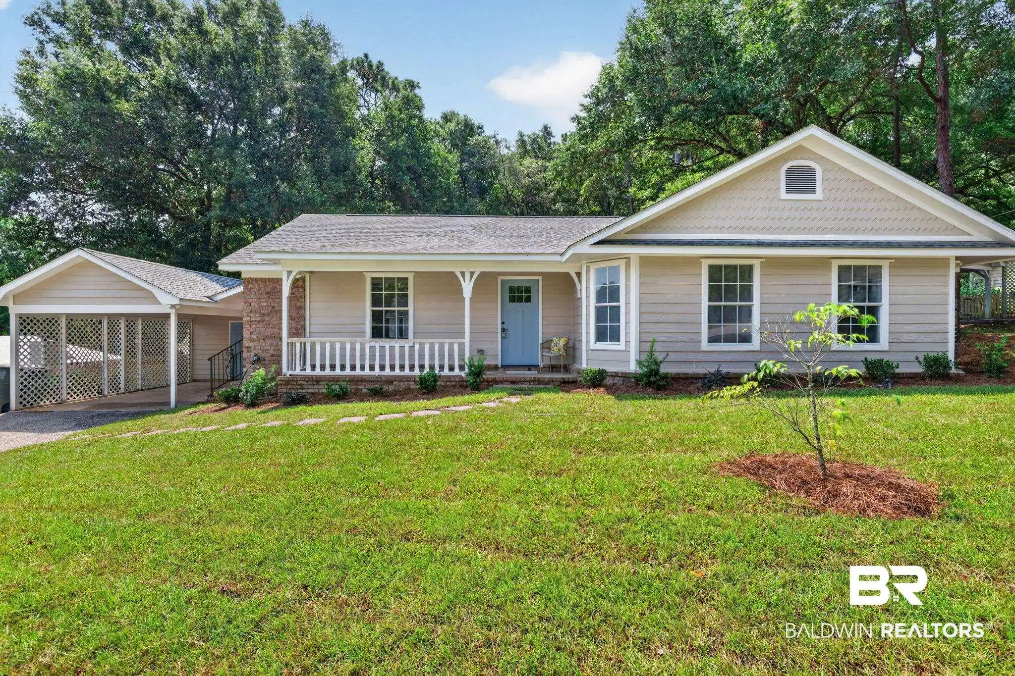Image 1: Single-story residence featuring light-toned siding, a covered front porch with white railing, and a light blue entry door