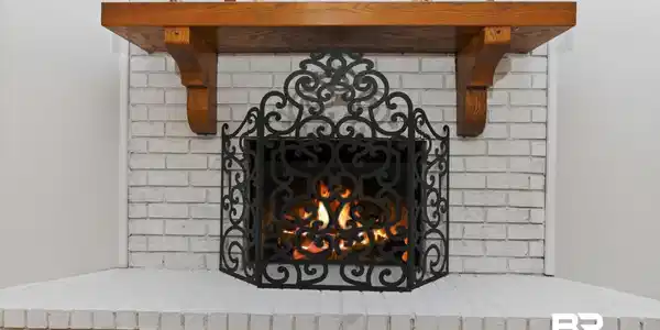 Image 4: White-painted brick fireplace featuring a decorative wrought-iron screen